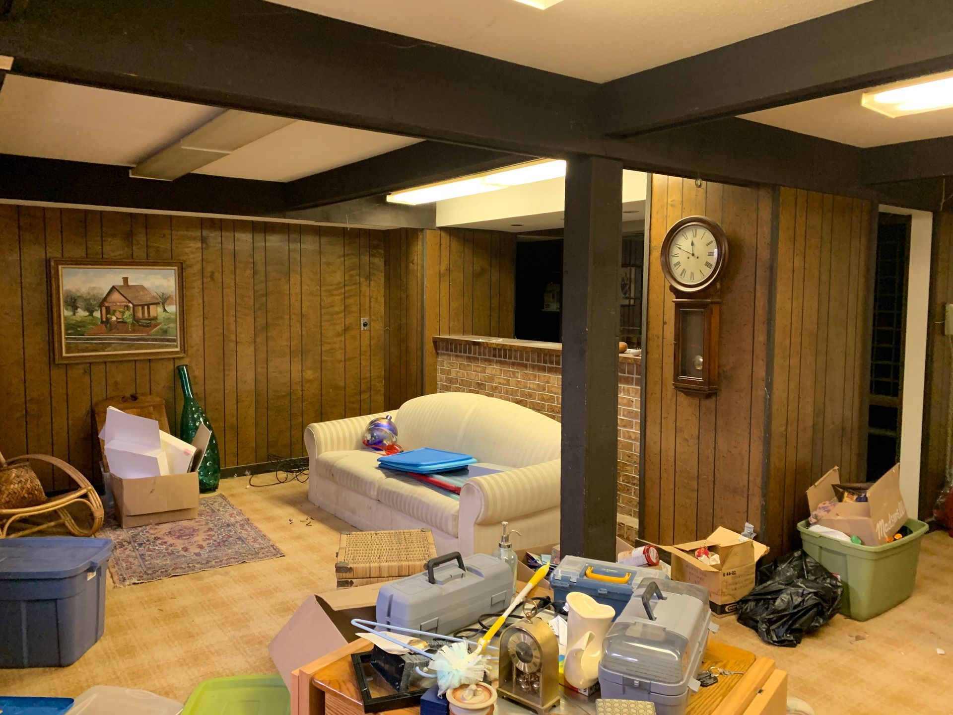 A living room with a couch and a clock on the wall.