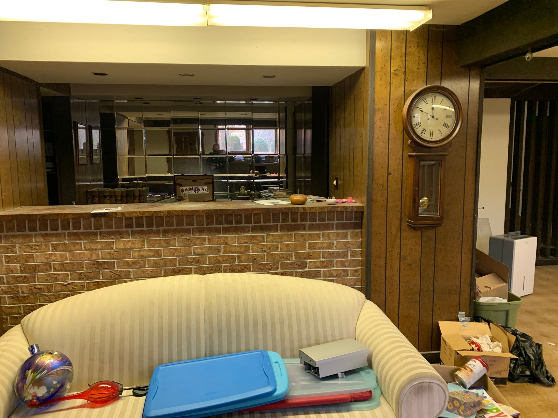 A living room with a couch and a clock on the wall.