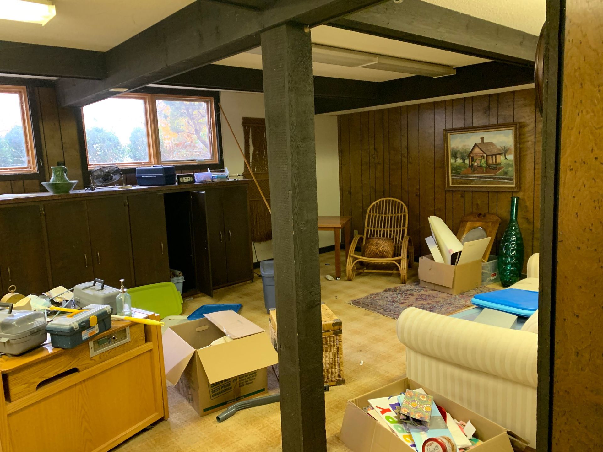 A living room with a couch , chairs , boxes and a picture on the wall.