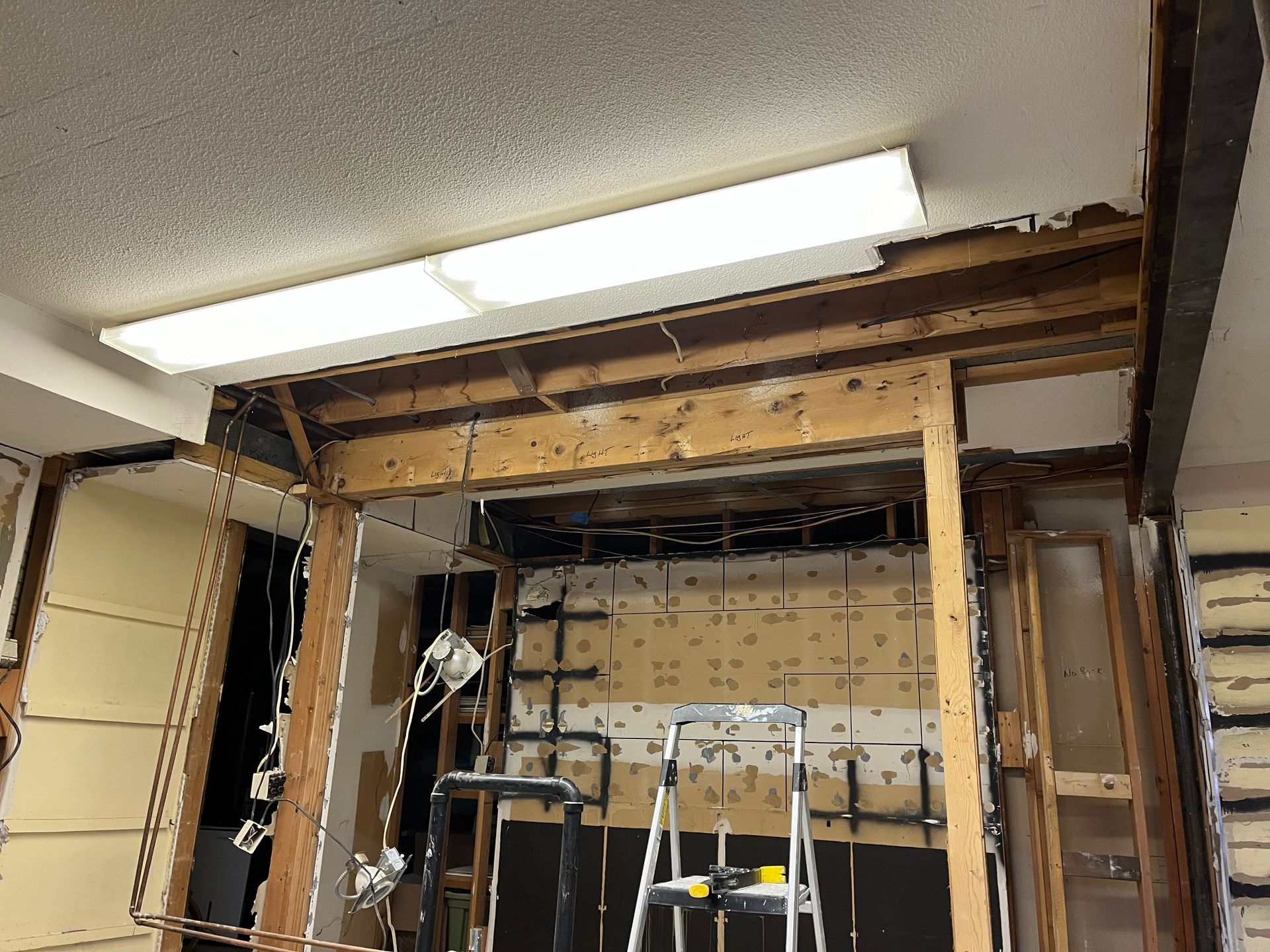 A room with a ladder and a light on the ceiling.