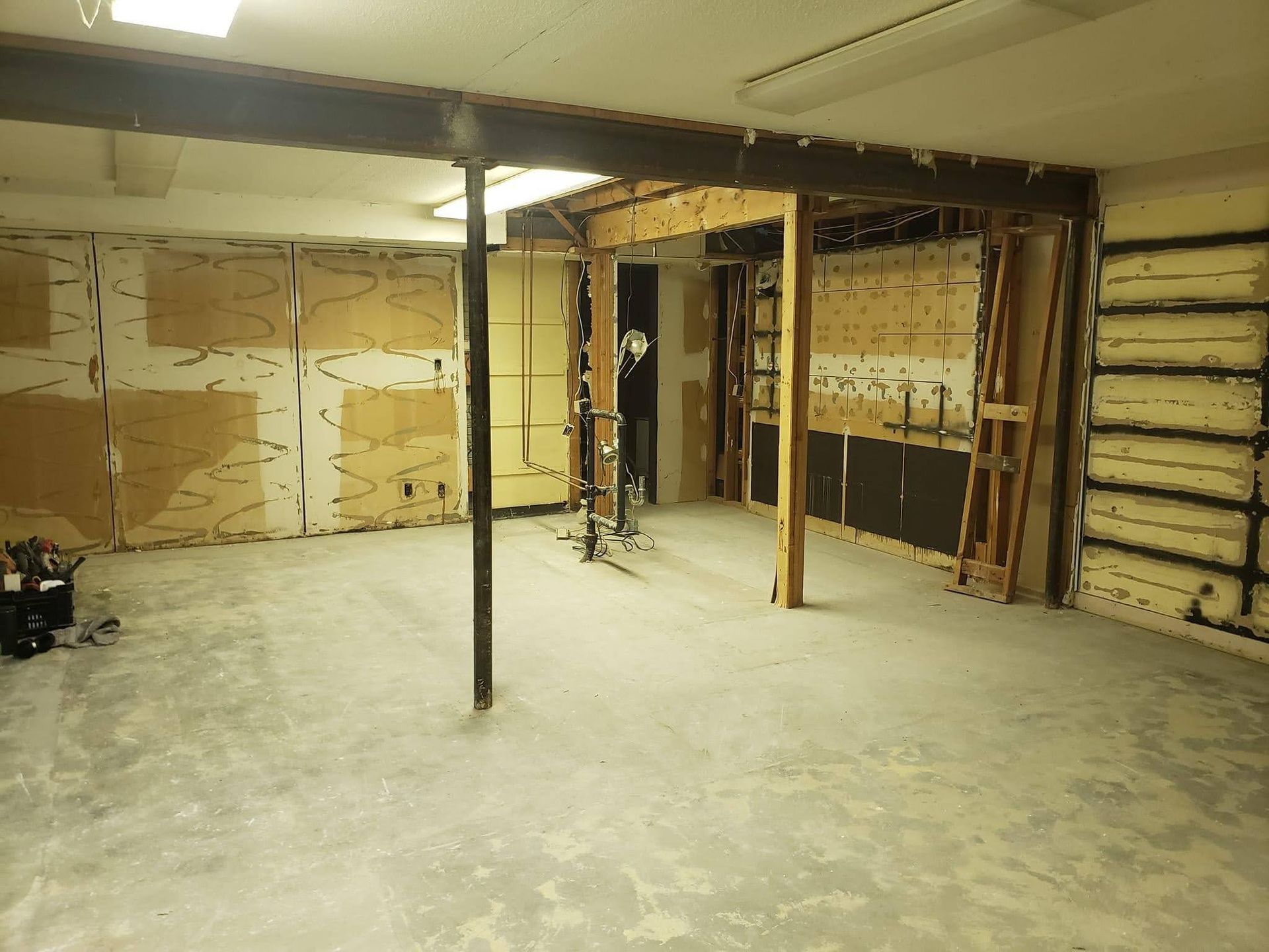 An empty basement with a concrete floor and wooden beams