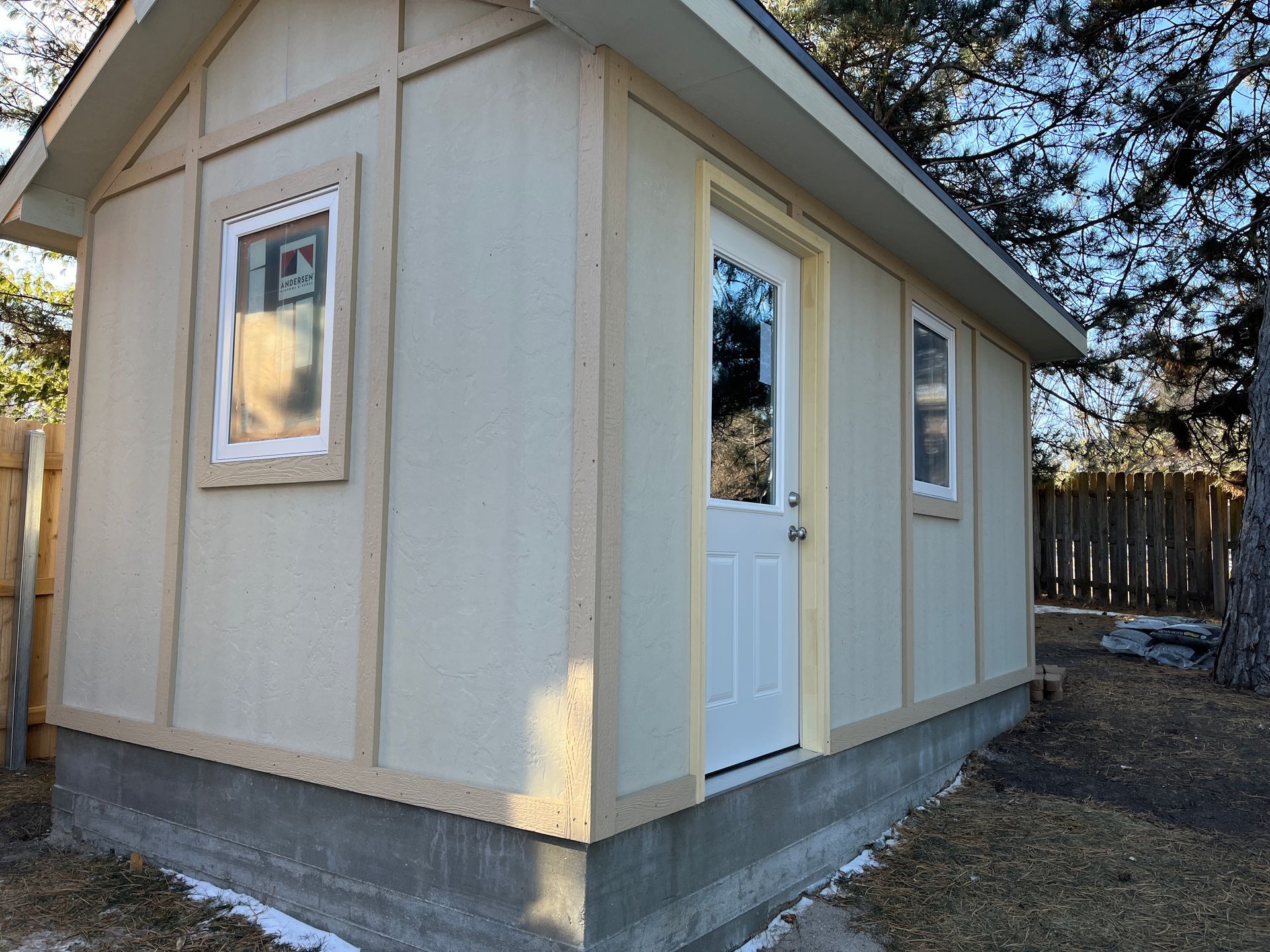 A garden shed with a white door and two windows