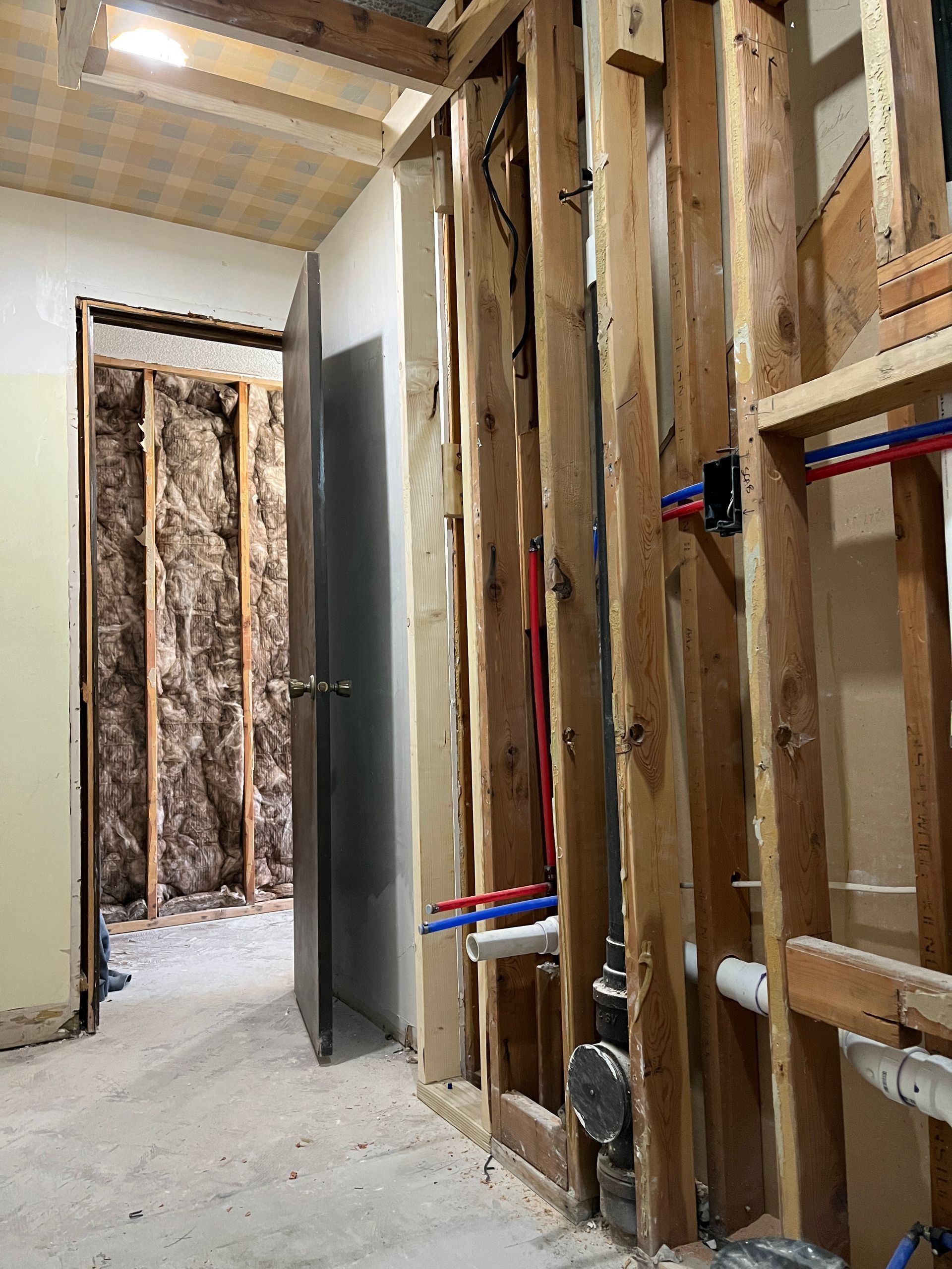 A room under construction with wooden walls and pipes.
