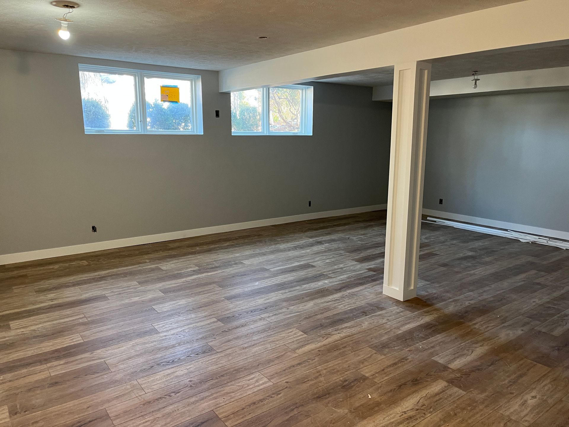 An empty basement with hardwood floors and gray walls.