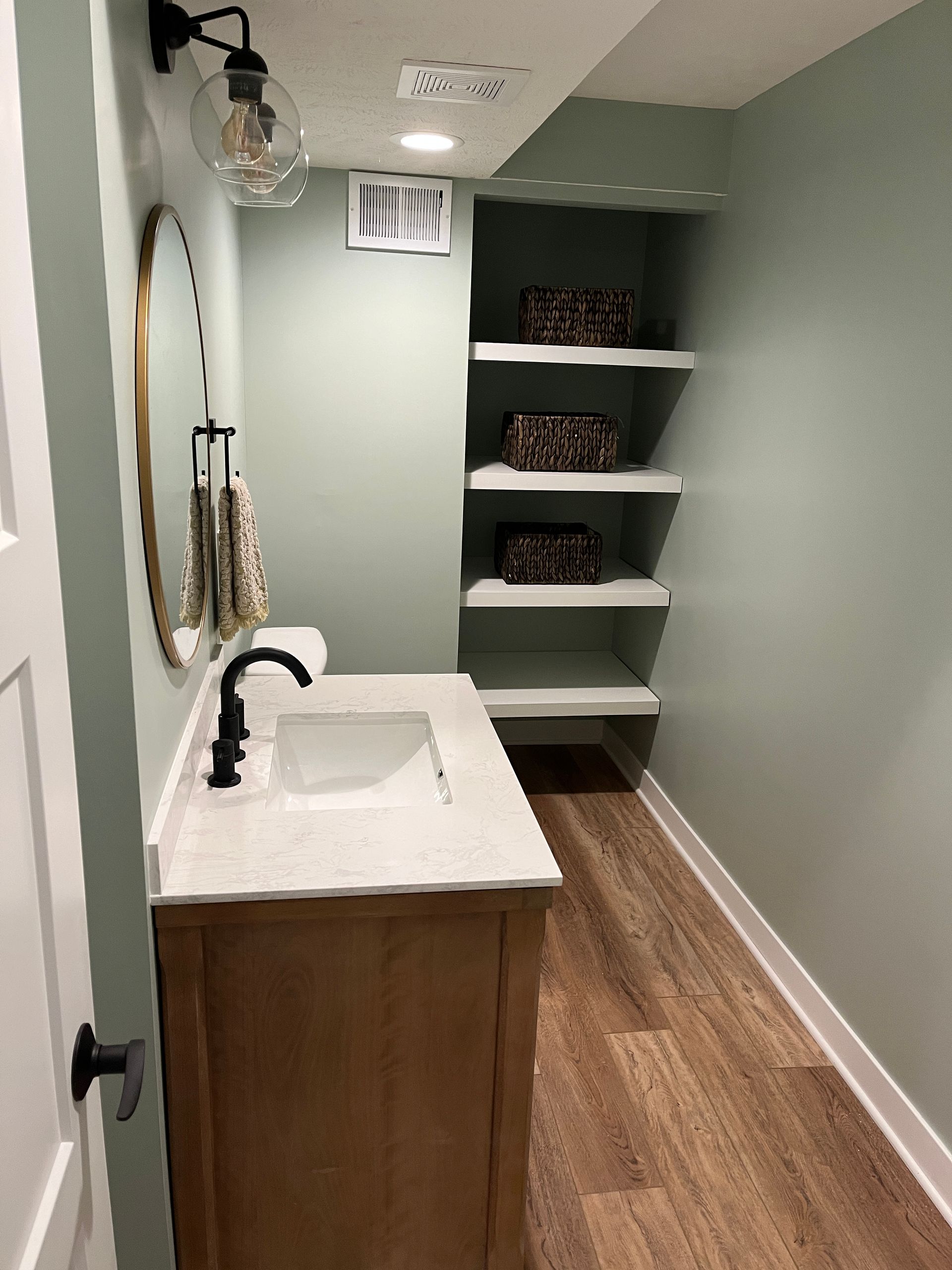 A bathroom with a sink , mirror and shelves.