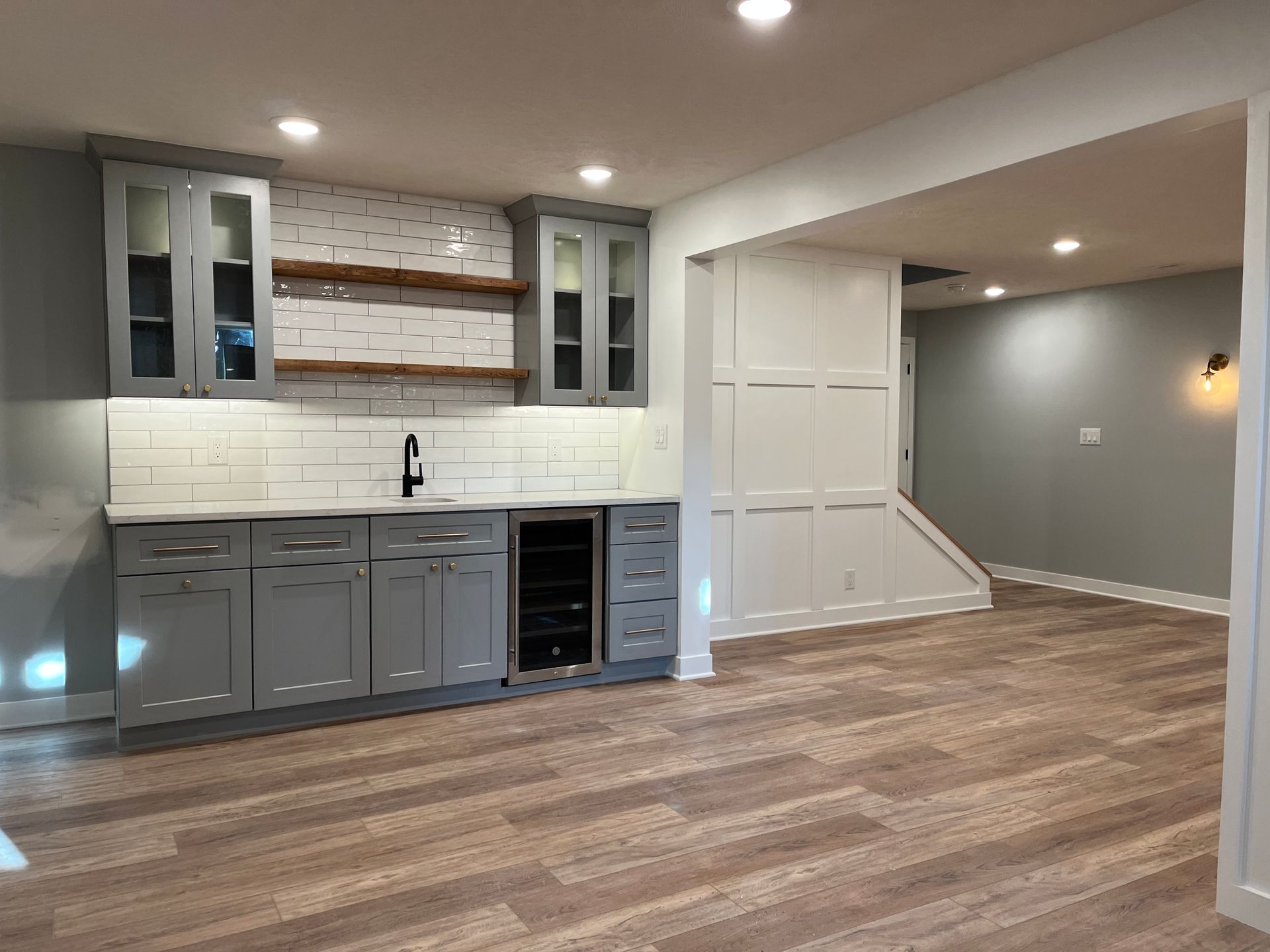 An empty basement with a bar and a refrigerator.