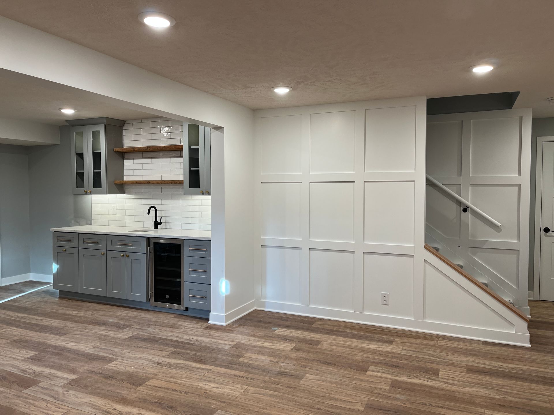 An empty basement with a kitchen and stairs.
