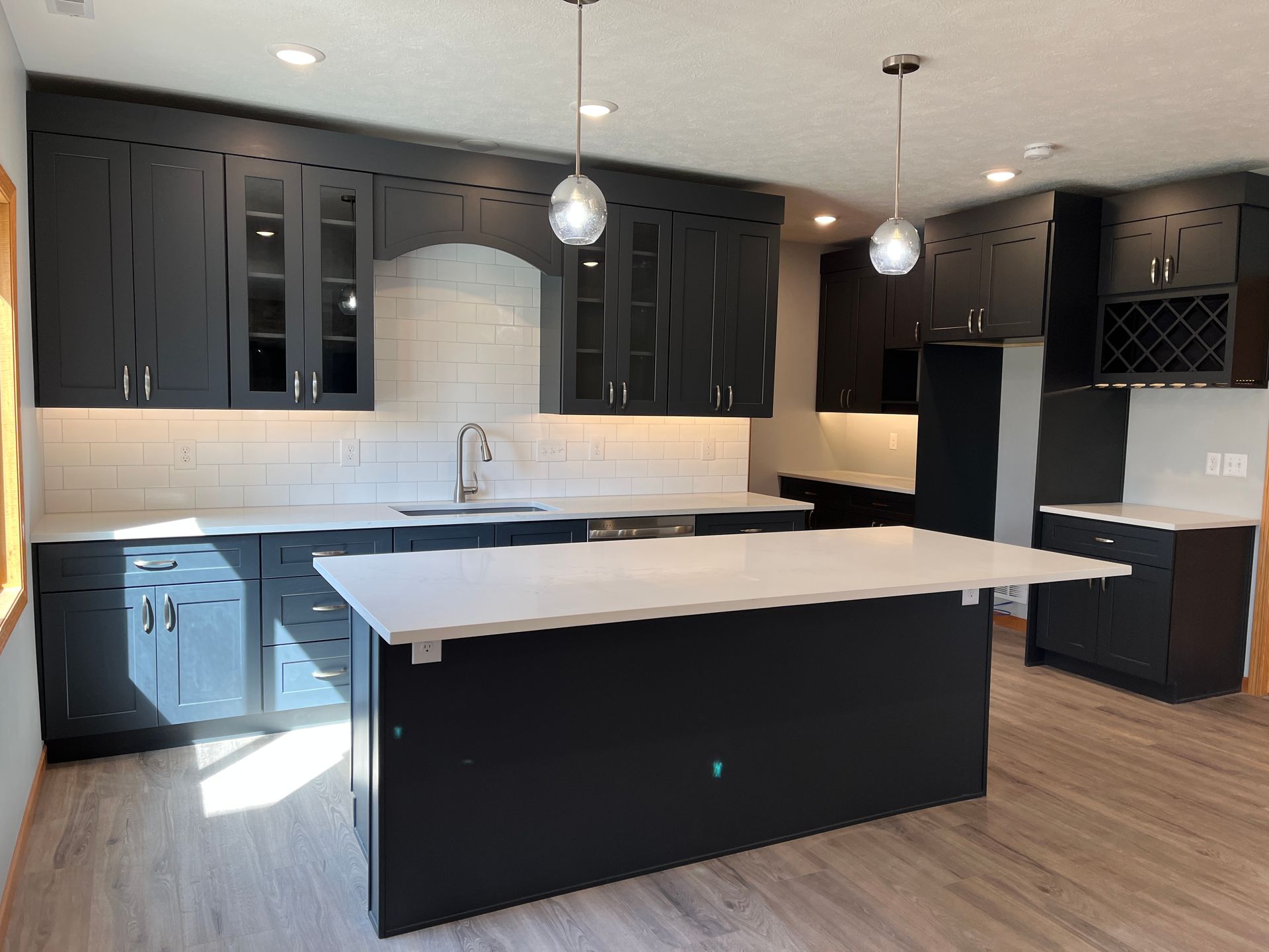A kitchen with black cabinets and a large island in the middle.