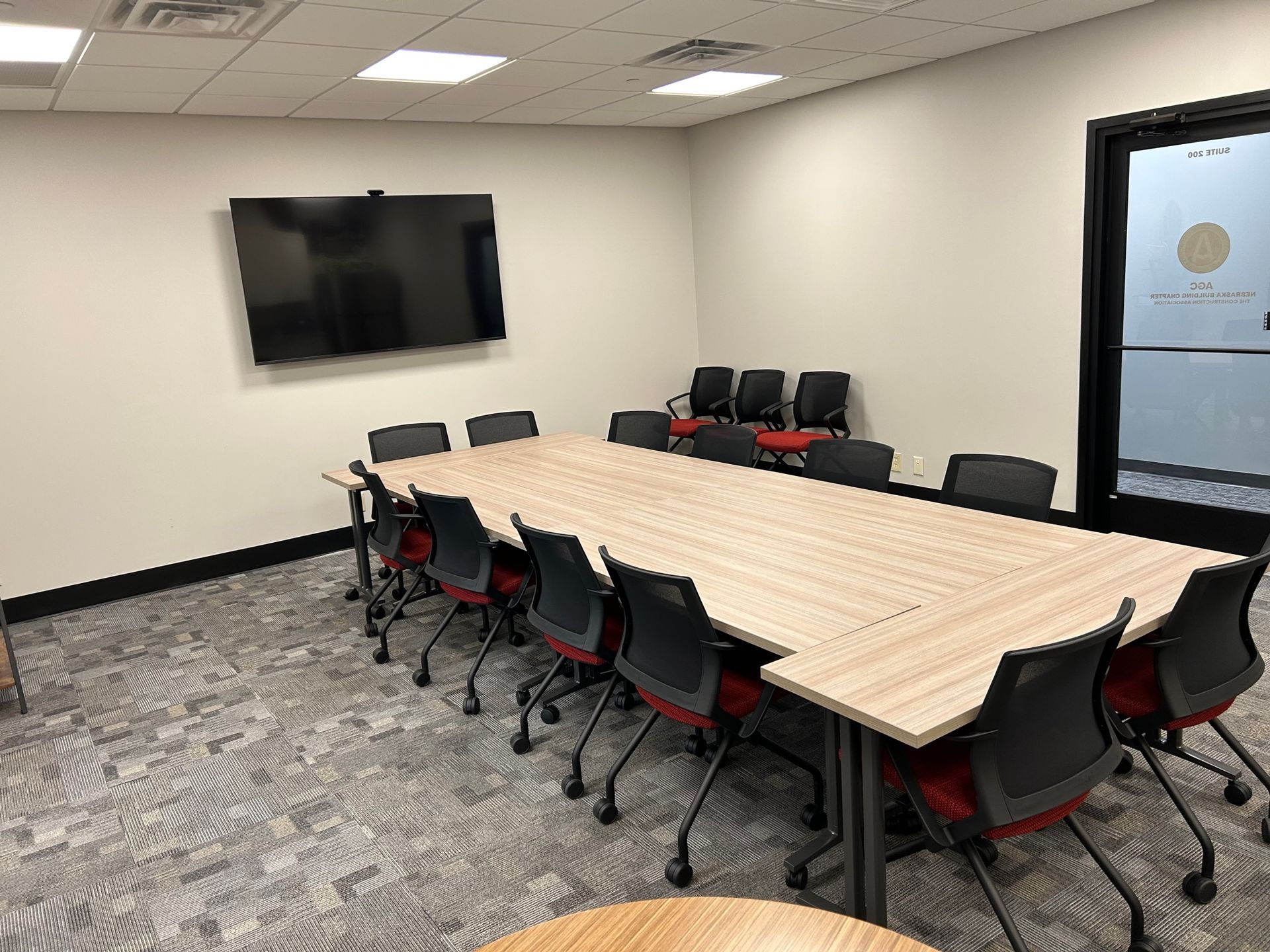 A conference room with a long table and chairs and a flat screen tv.