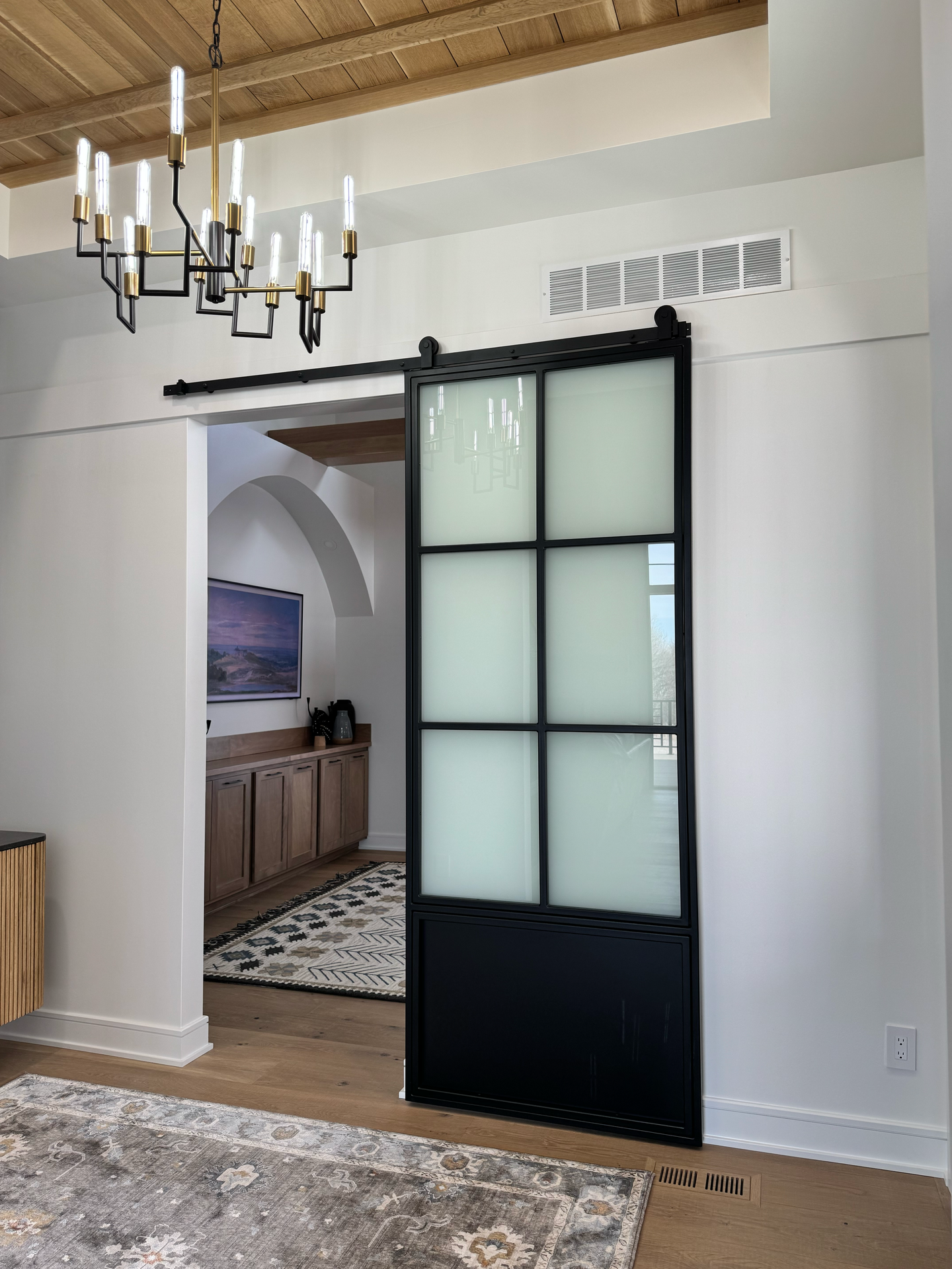 A living room with a sliding barn door and a chandelier.