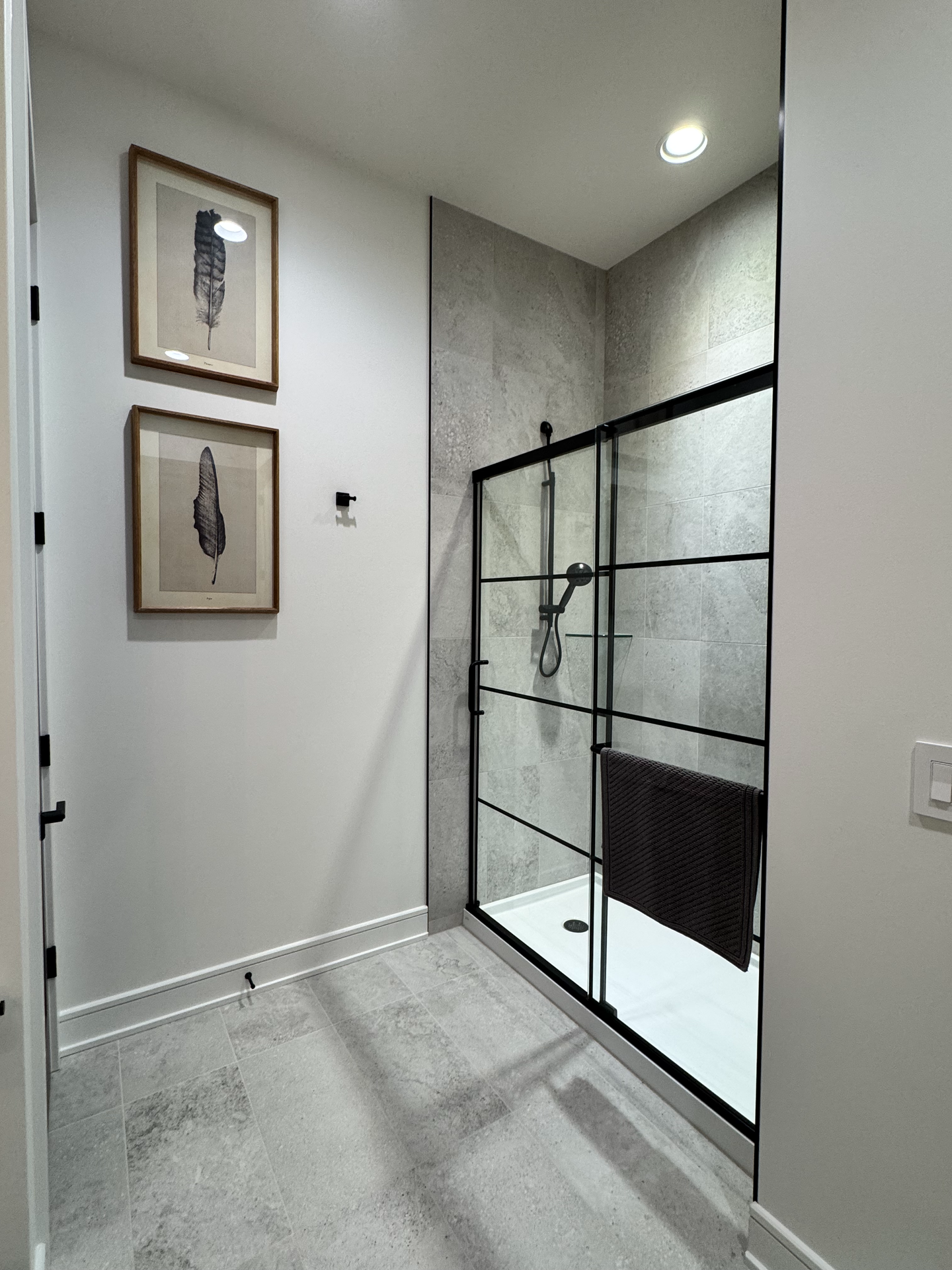 A bathroom with a walk in shower and two pictures on the wall.