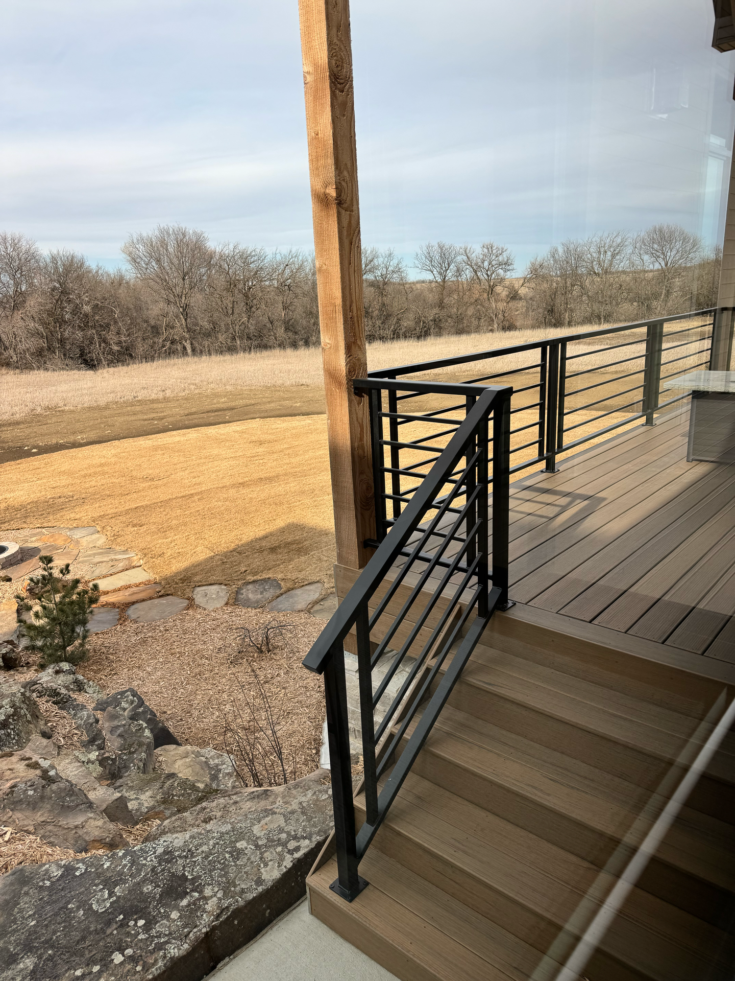A wooden deck with a metal railing and stairs leading up to it.