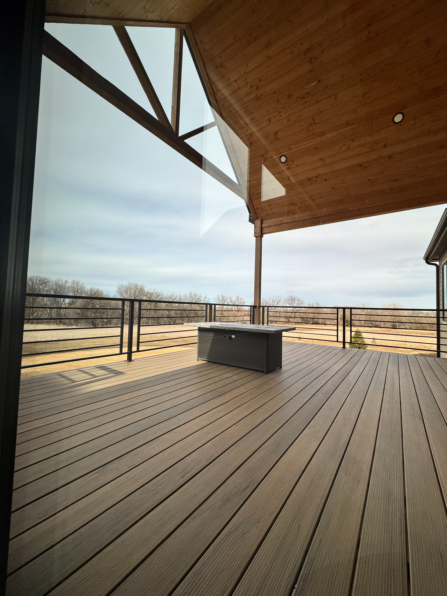 A wooden deck with a bench on it and a view of a field.