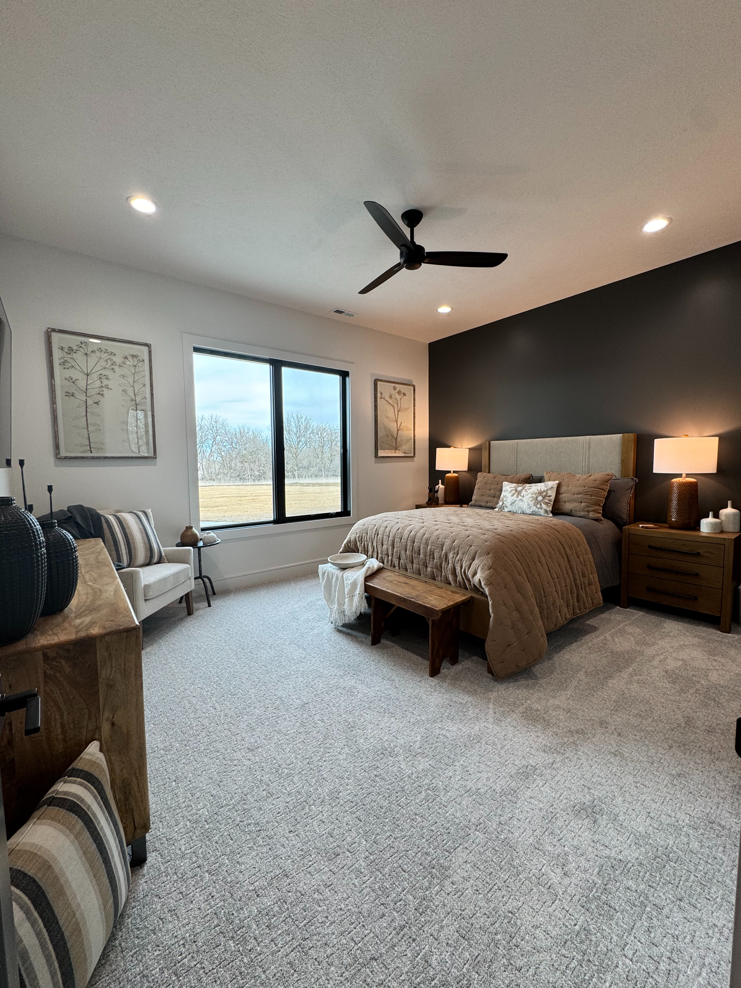 A bedroom with a ceiling fan , a bed , a chair , and a dresser.