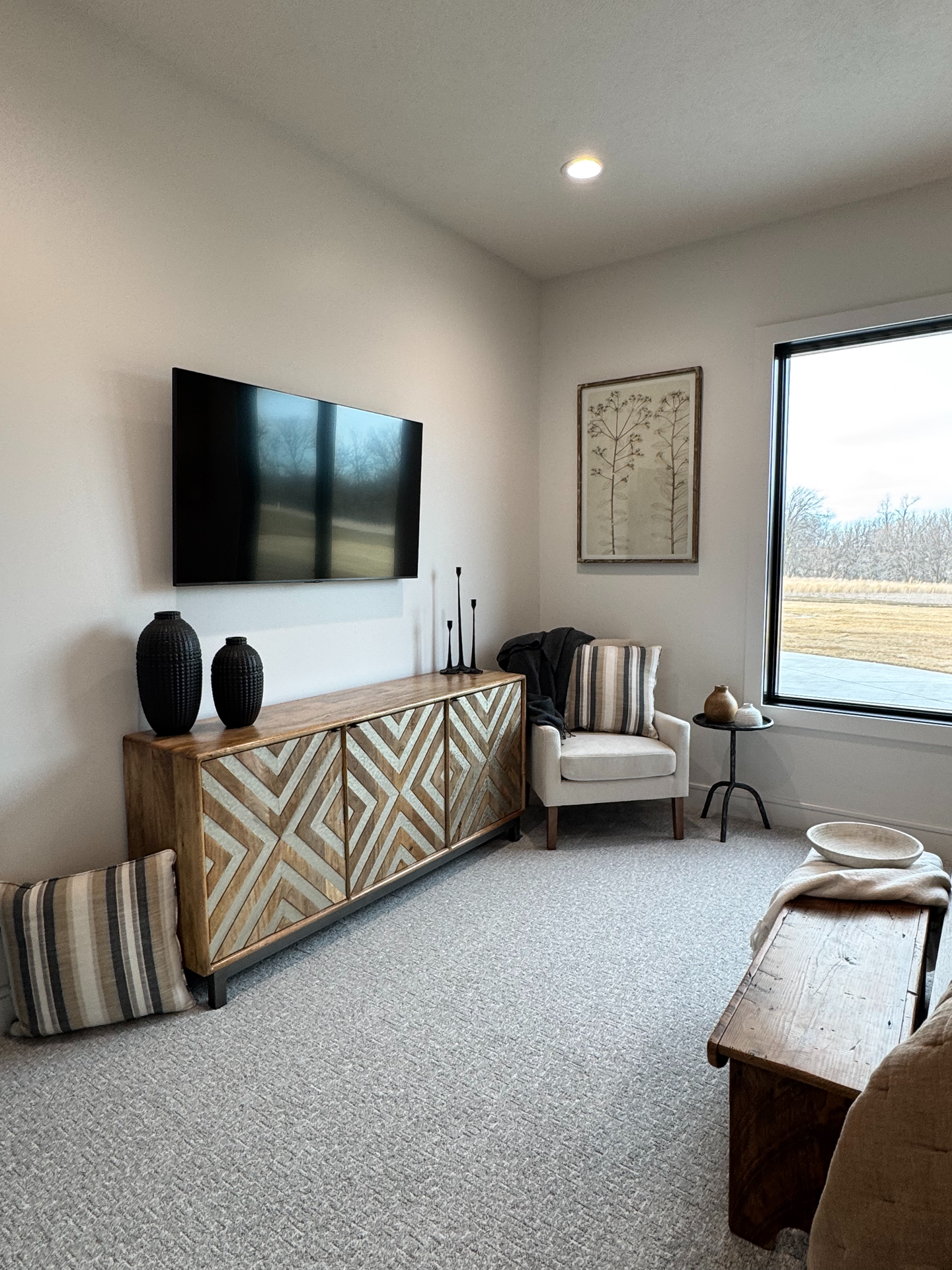 A living room with a couch , chair , television and a window.