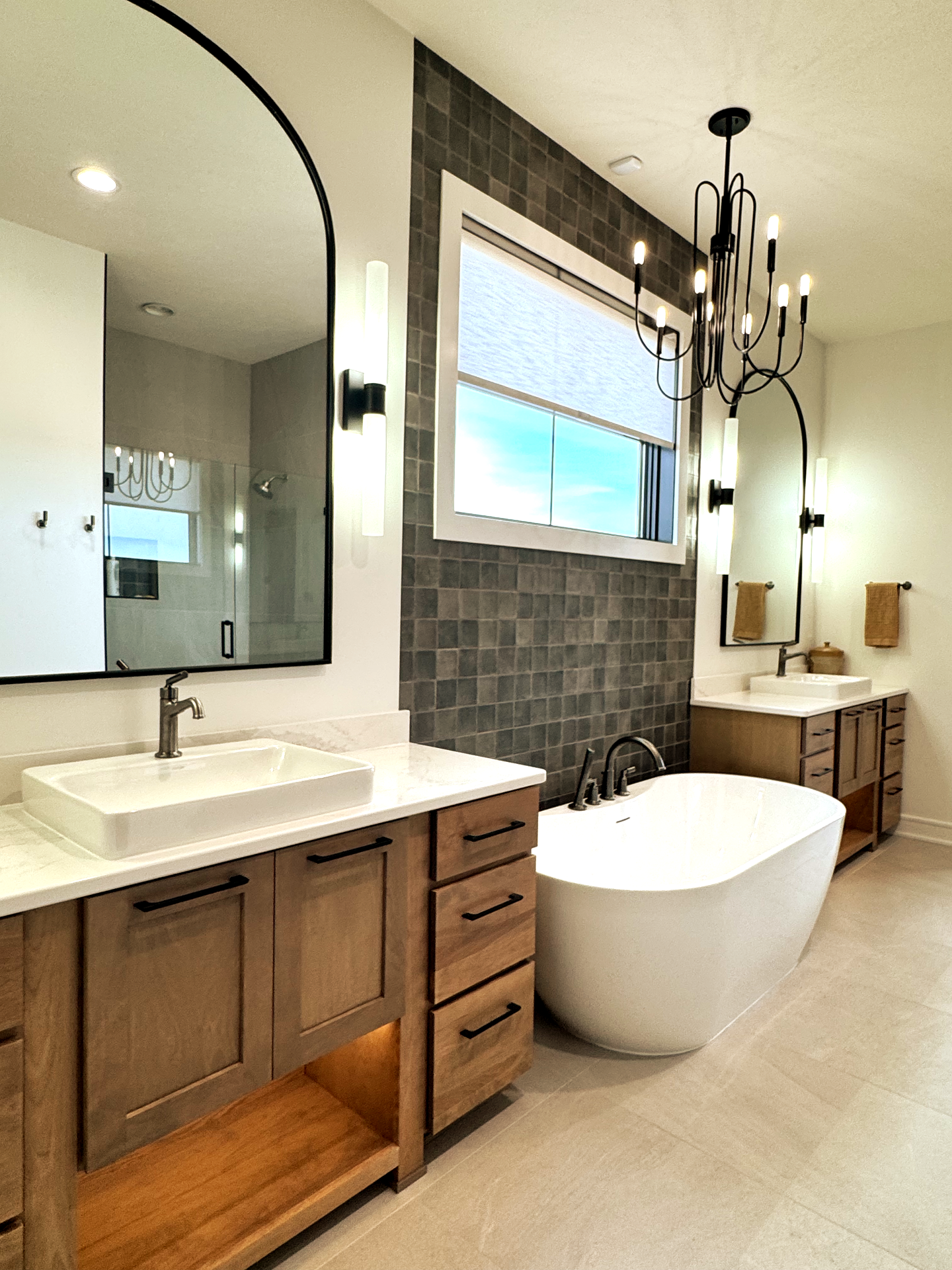 A bathroom with two sinks , a tub , and a large mirror.