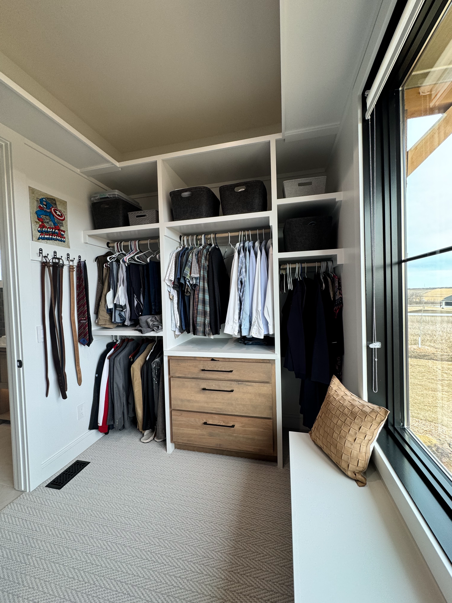 A walk in closet with lots of clothes and a window.
