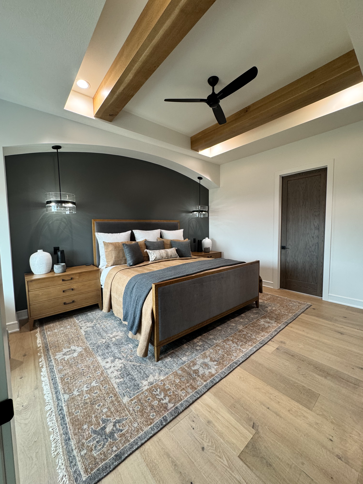 A bedroom with a bed , dresser , nightstand , rug and ceiling fan.