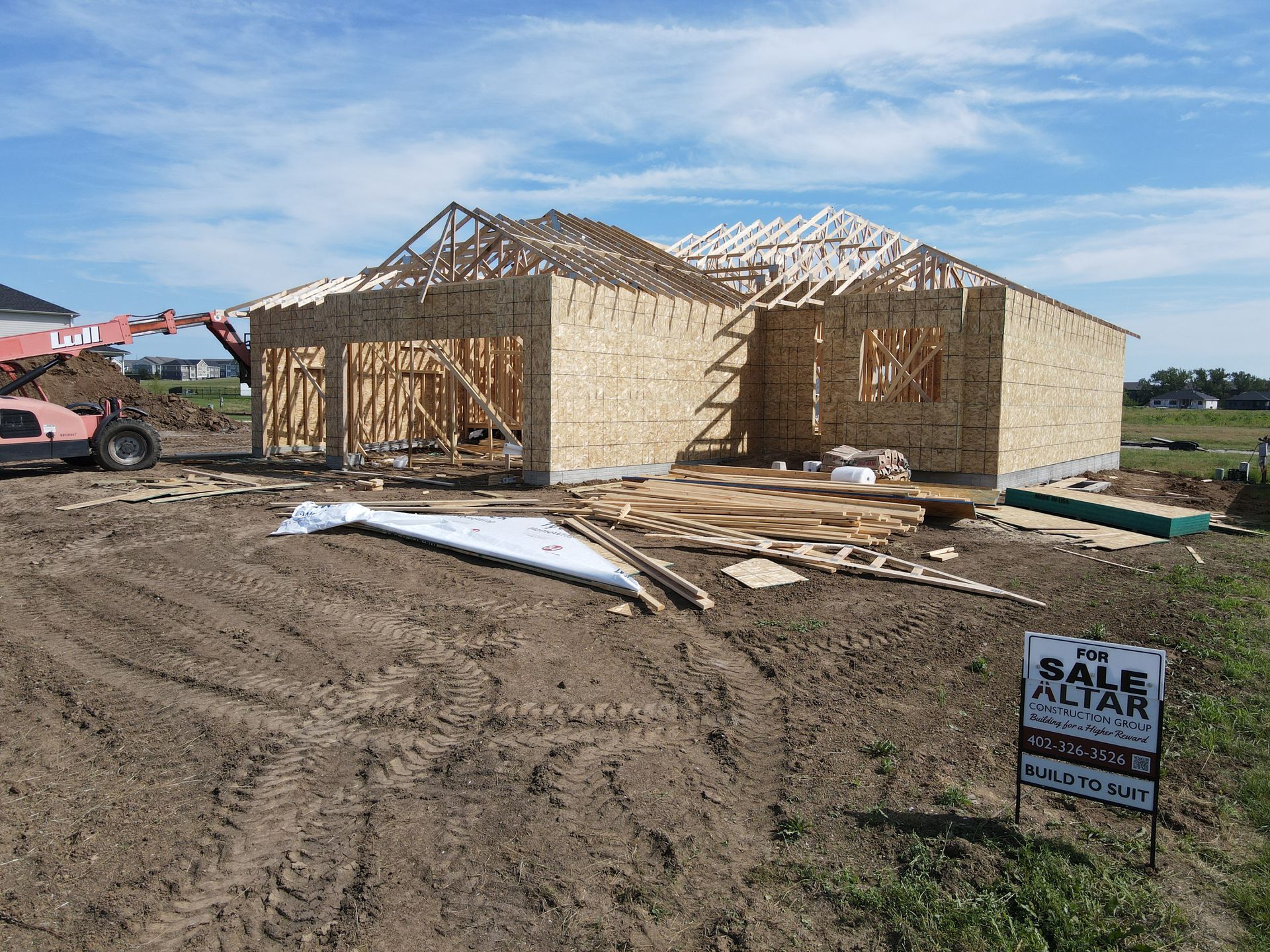 House under construction, wooden frame, partially roofed. Sign for