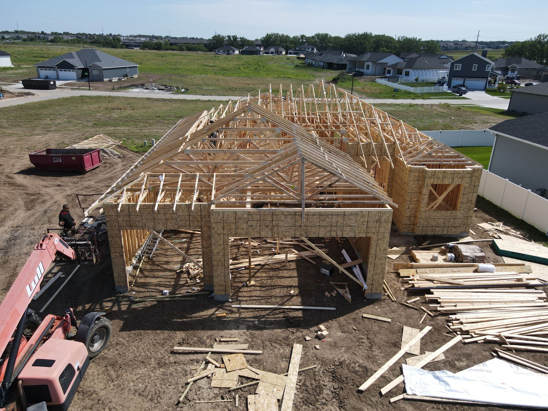 A house under construction; wooden frame visible with garage and roof trusses in place.