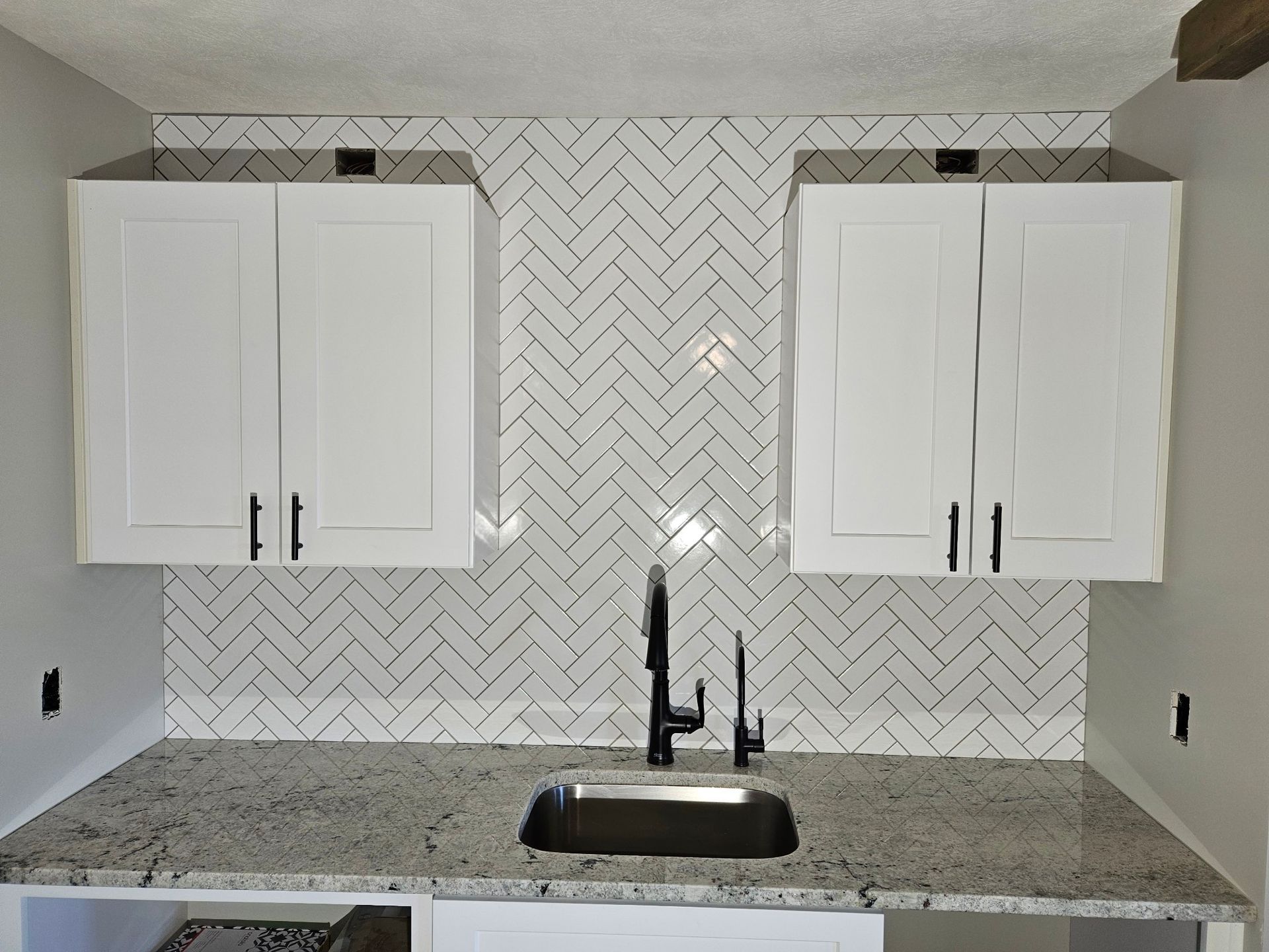 A kitchen with white cabinets and a black sink
