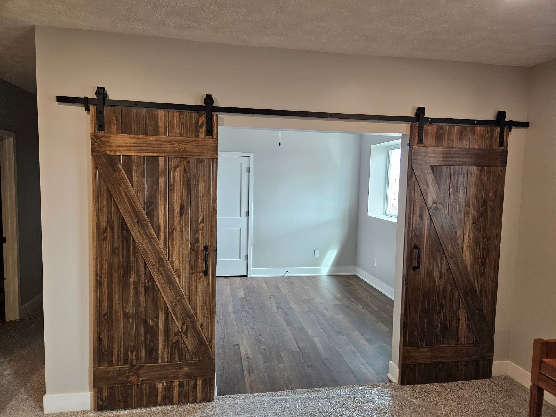 A room with sliding barn doors leading to a living room.