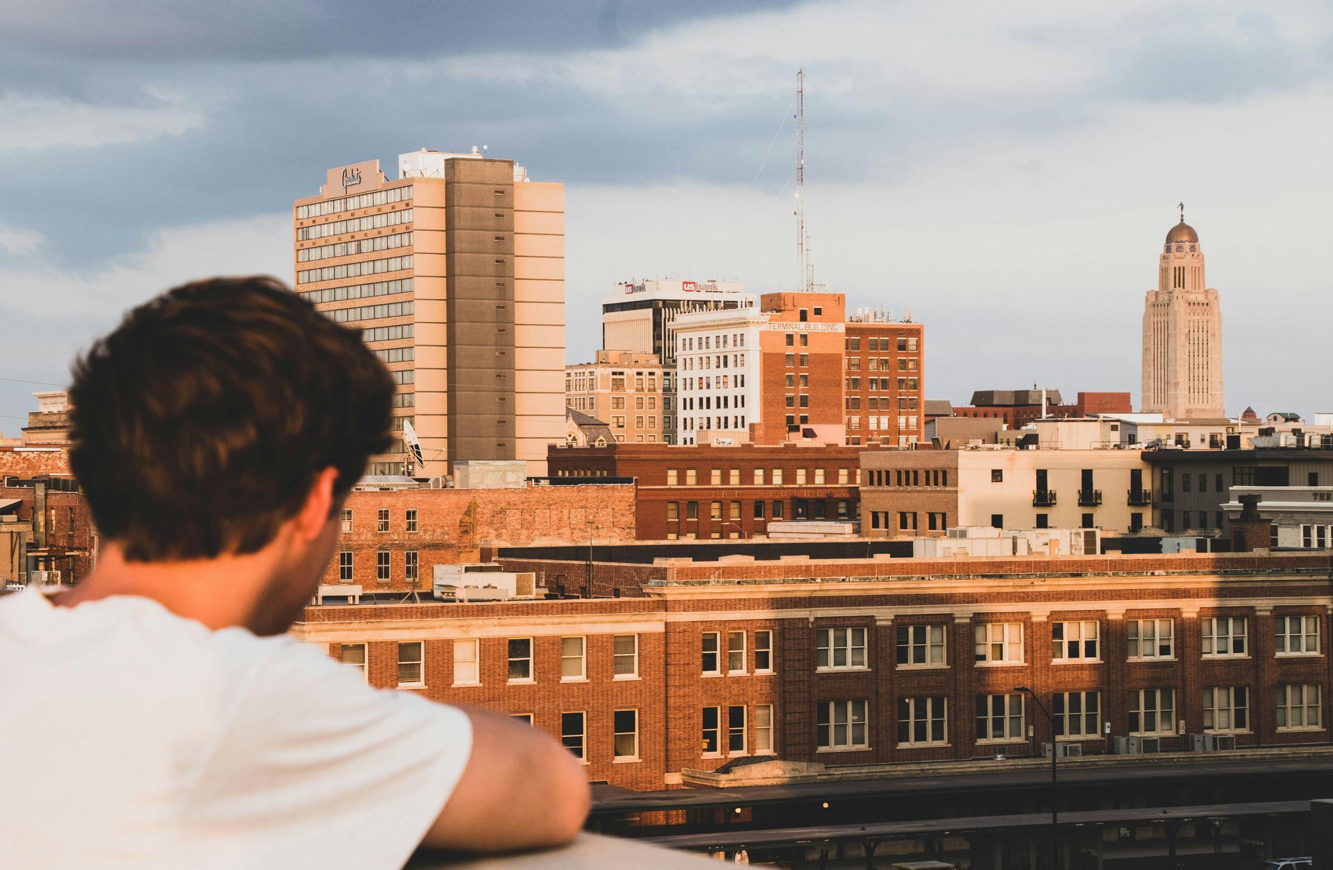 A man is looking at a city skyline from a balcony.