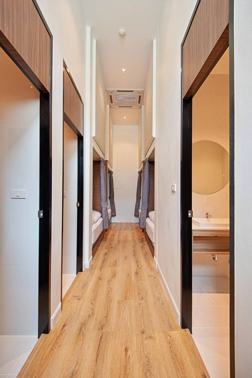 Long hallway with bunk beds and open doorways; wooden floors, neutral colors.
