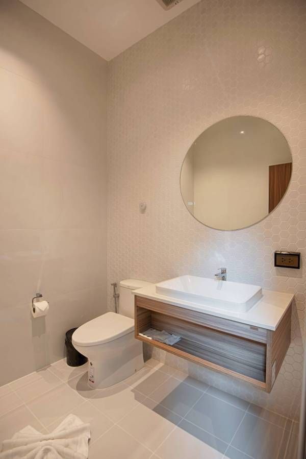 A modern bathroom with a white toilet, sink, and round mirror. Neutral tones, minimalist design.