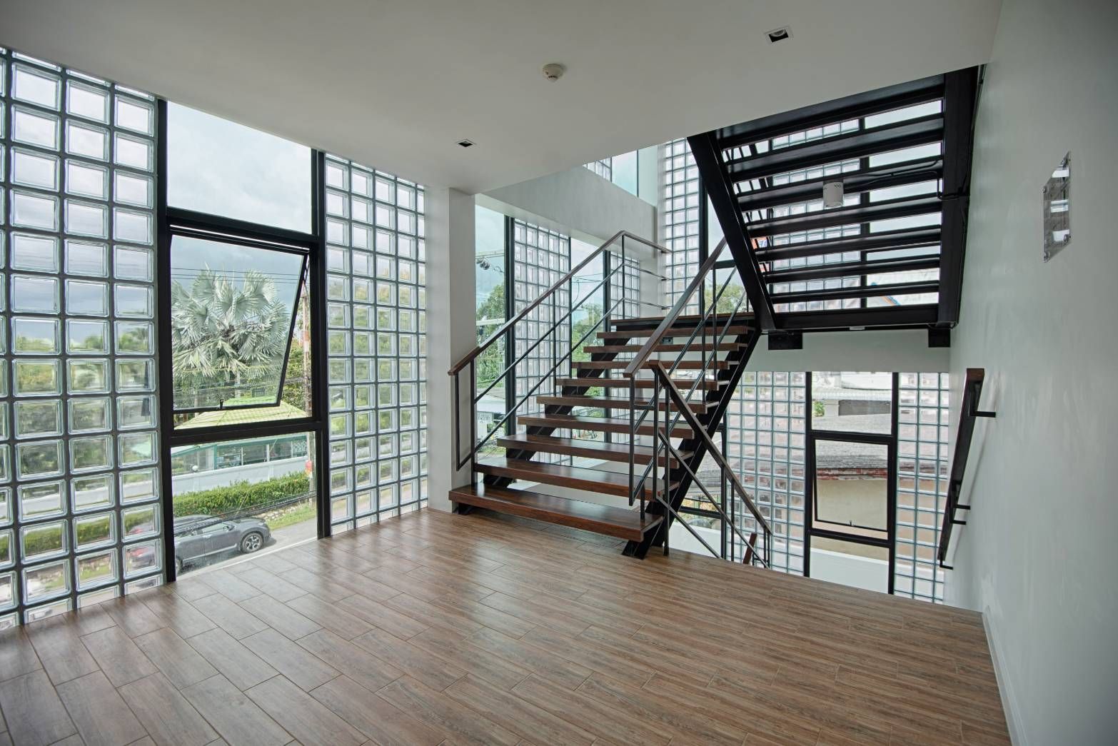 Interior with glass block windows, wooden staircase, and wood flooring.