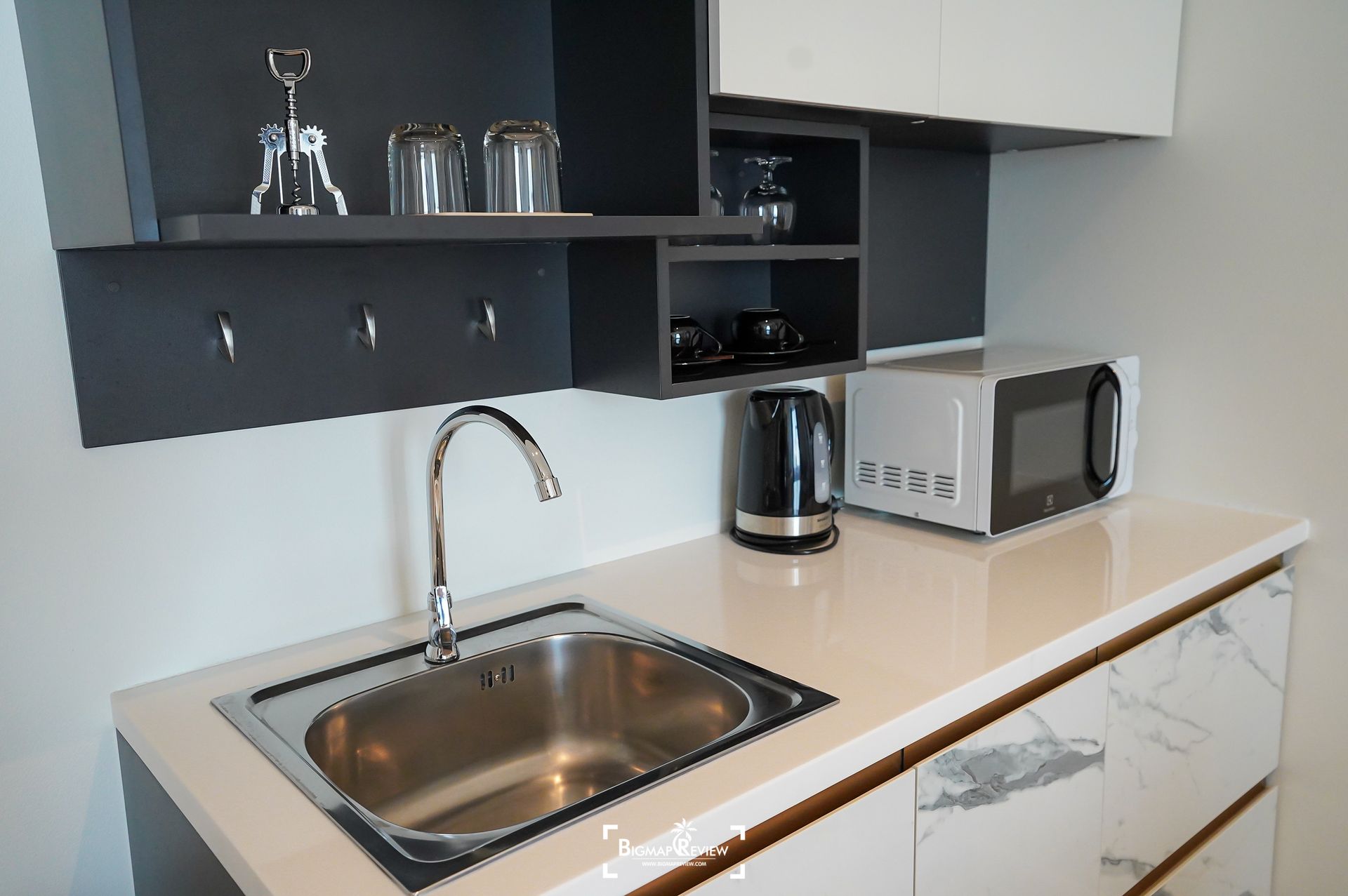 Kitchenette with sink, microwave, and cabinets in a light-colored setting.