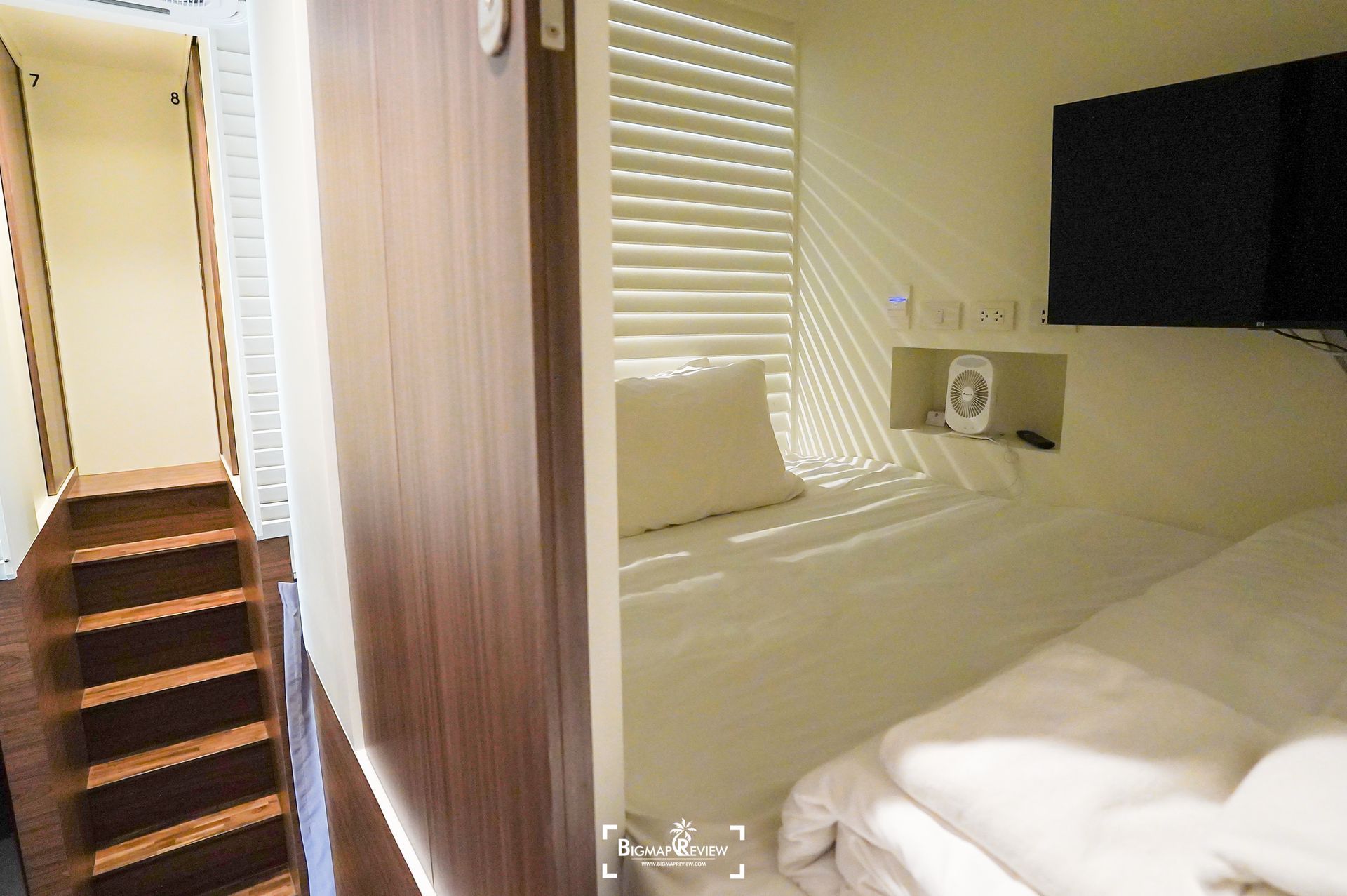 Bedroom interior with a bed, TV, and stairs leading up to an upper level.