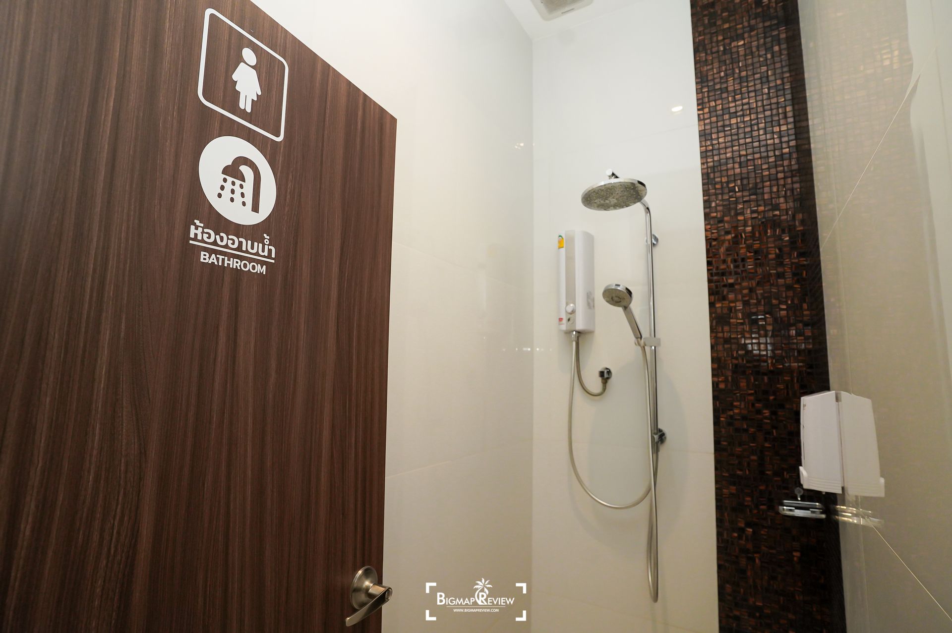Shower stall with a brown wood door labeled for women with shower fixtures.