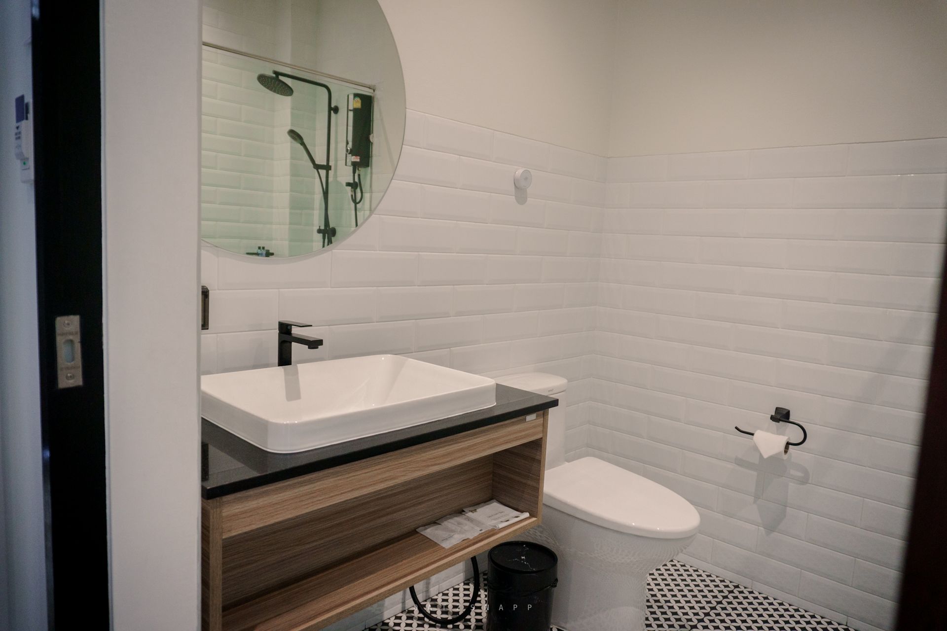 Bathroom with white brick wall, square sink, black faucet, and toilet.