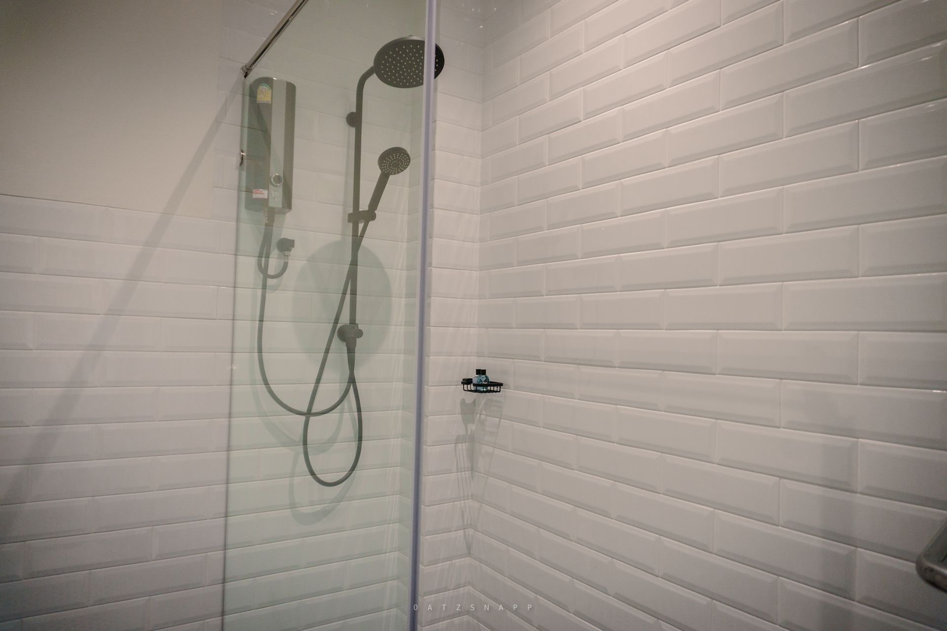 Shower stall with a glass door and white subway tile walls.