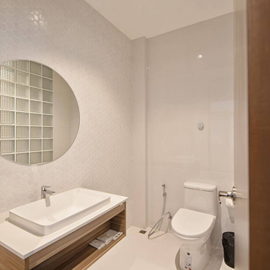 Modern bathroom with white walls, a rectangular sink, and a round mirror.