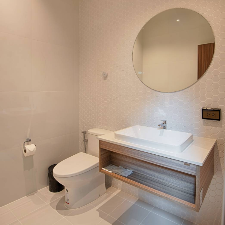 Modern bathroom with a white sink, round mirror, and toilet.