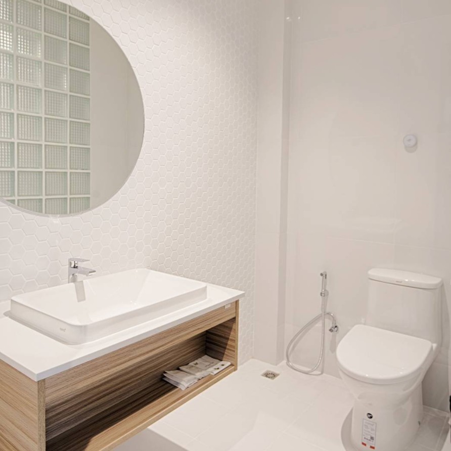 Modern white bathroom with floating vanity, round mirror, and toilet.