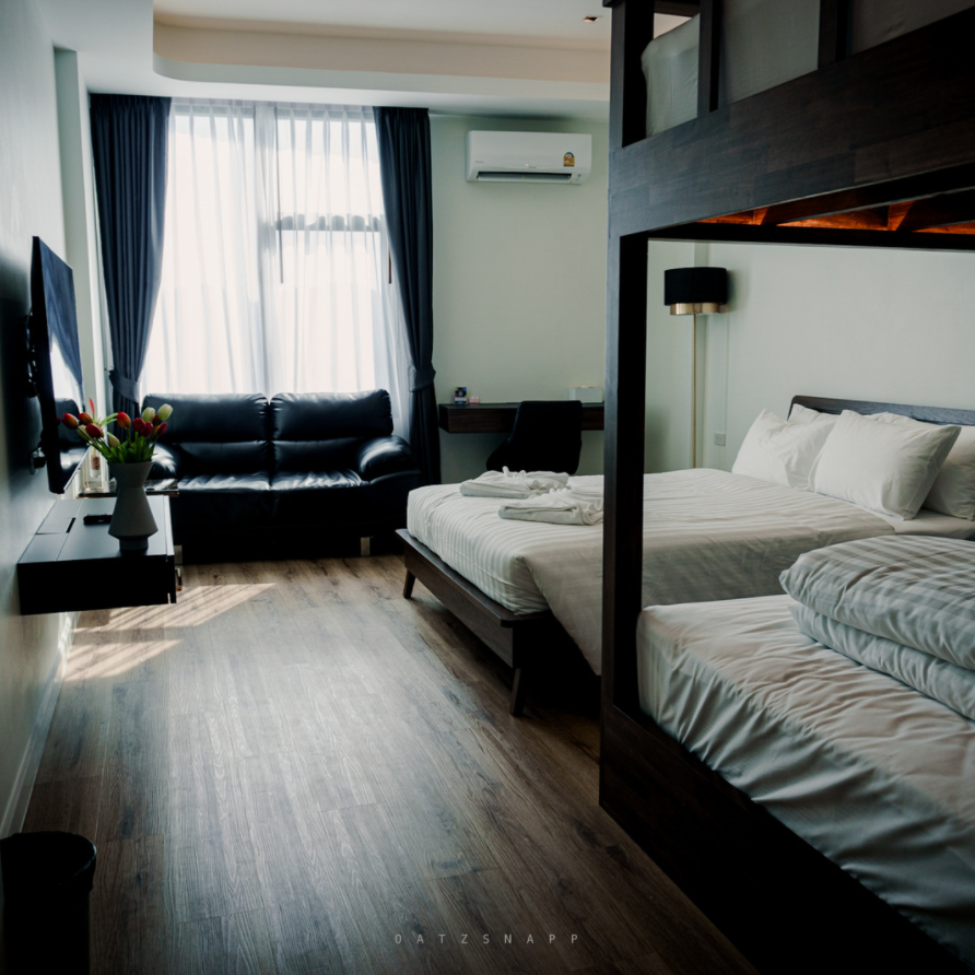 Hotel room with bunk bed, double bed, sofa, desk, and TV.