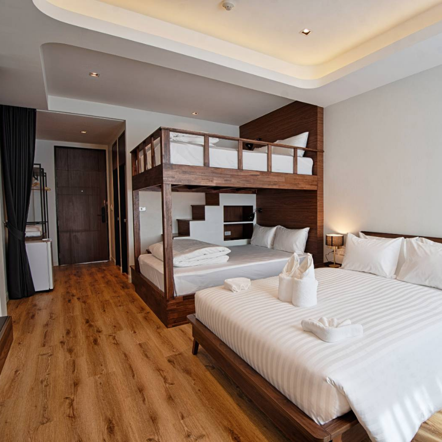 Hotel room with bunk beds, a double bed, wooden floors, and a white and brown color scheme.