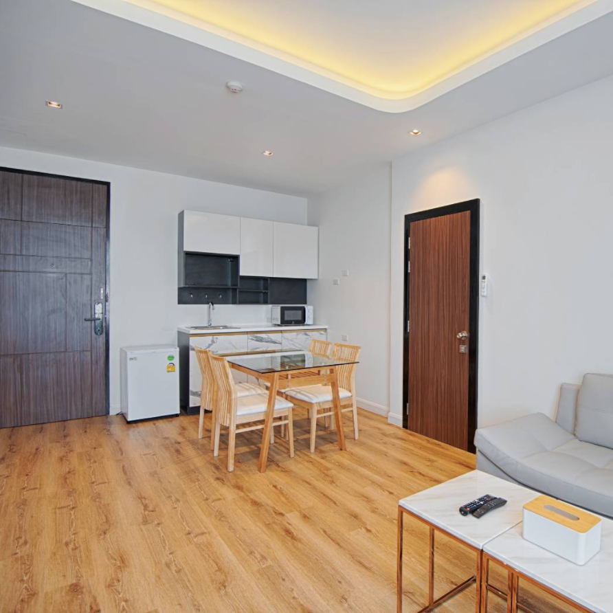 A modern apartment interior with kitchen, dining area, and living space; light wood floors, white walls.