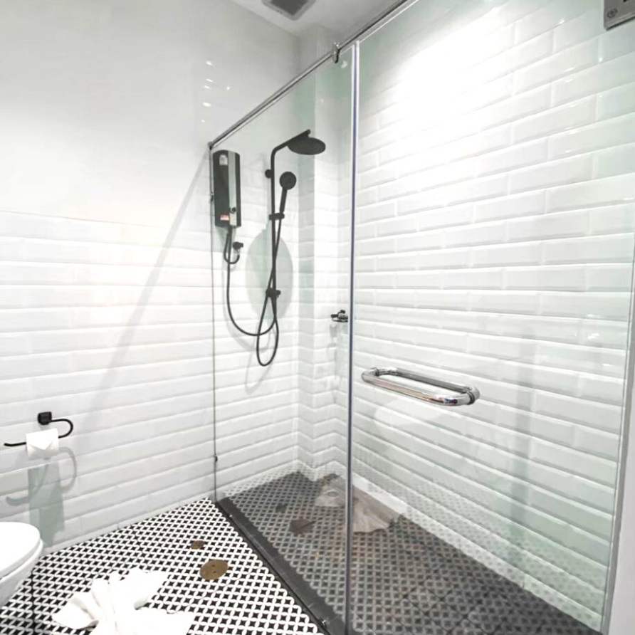Modern bathroom with a glass shower, white subway tiles, and black and white patterned floor.
