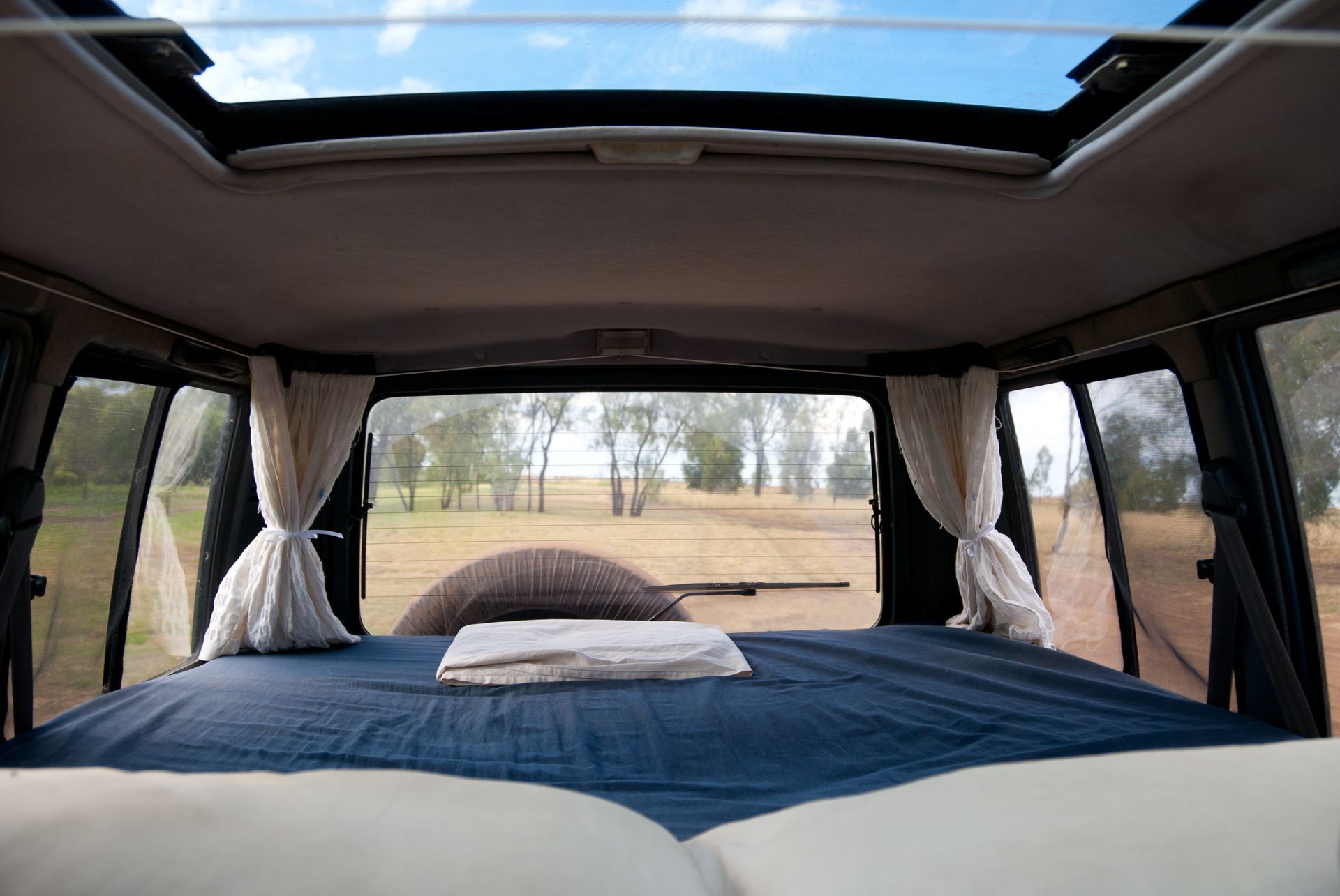 The inside of a van with a bed and a skylight.