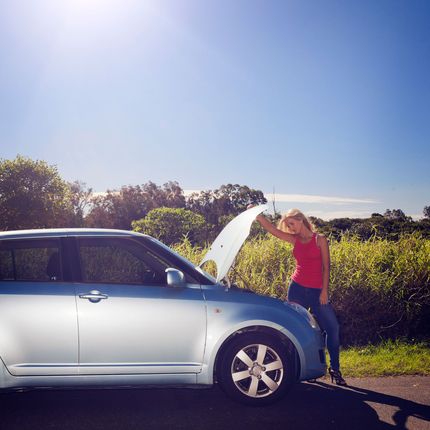 A woman stands next to a blue car with the hood up
