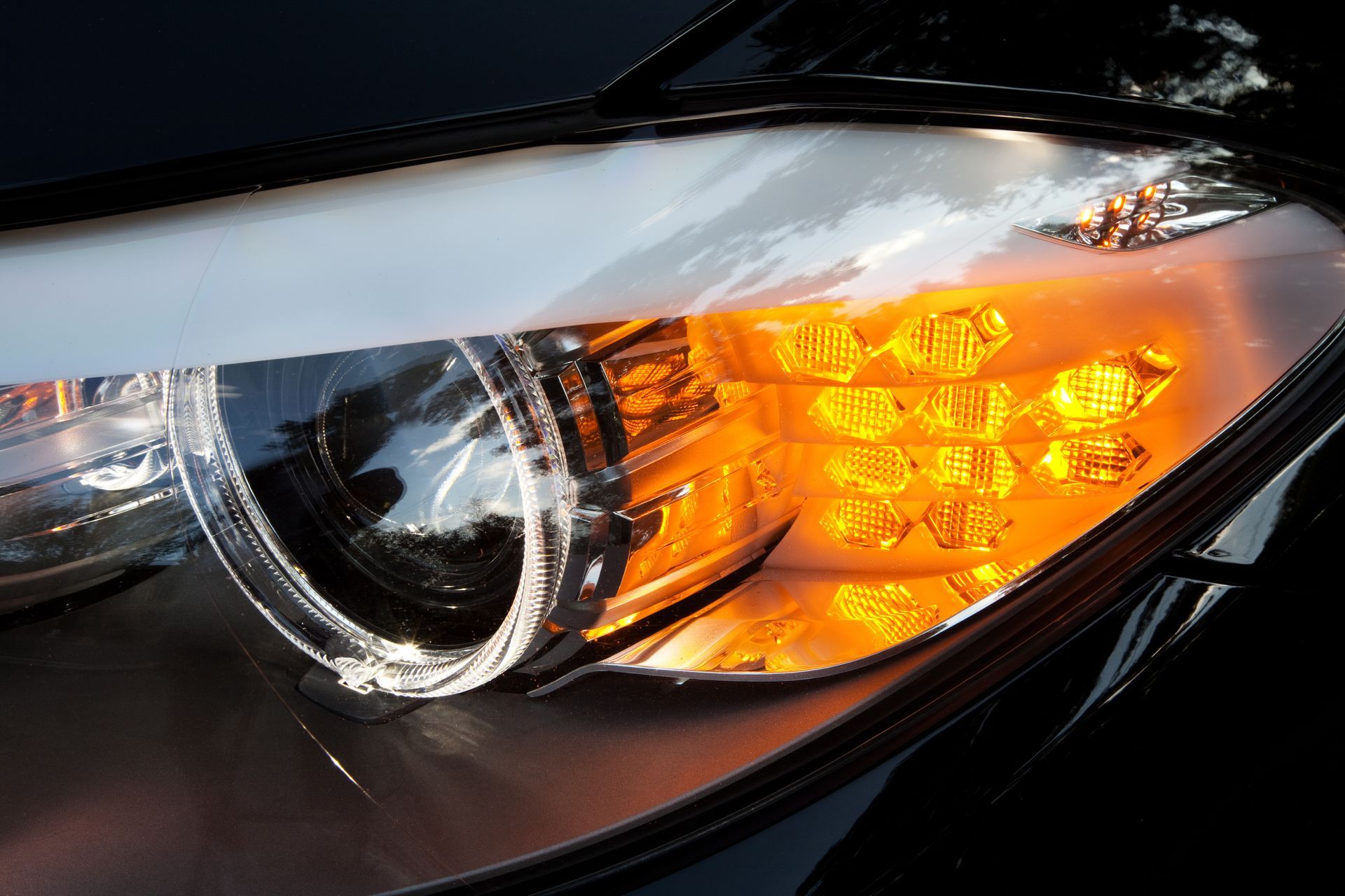 A close up of a car headlight with orange lights on