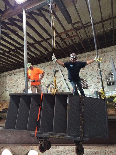 two men are working on a large piece of metal in a warehouse .