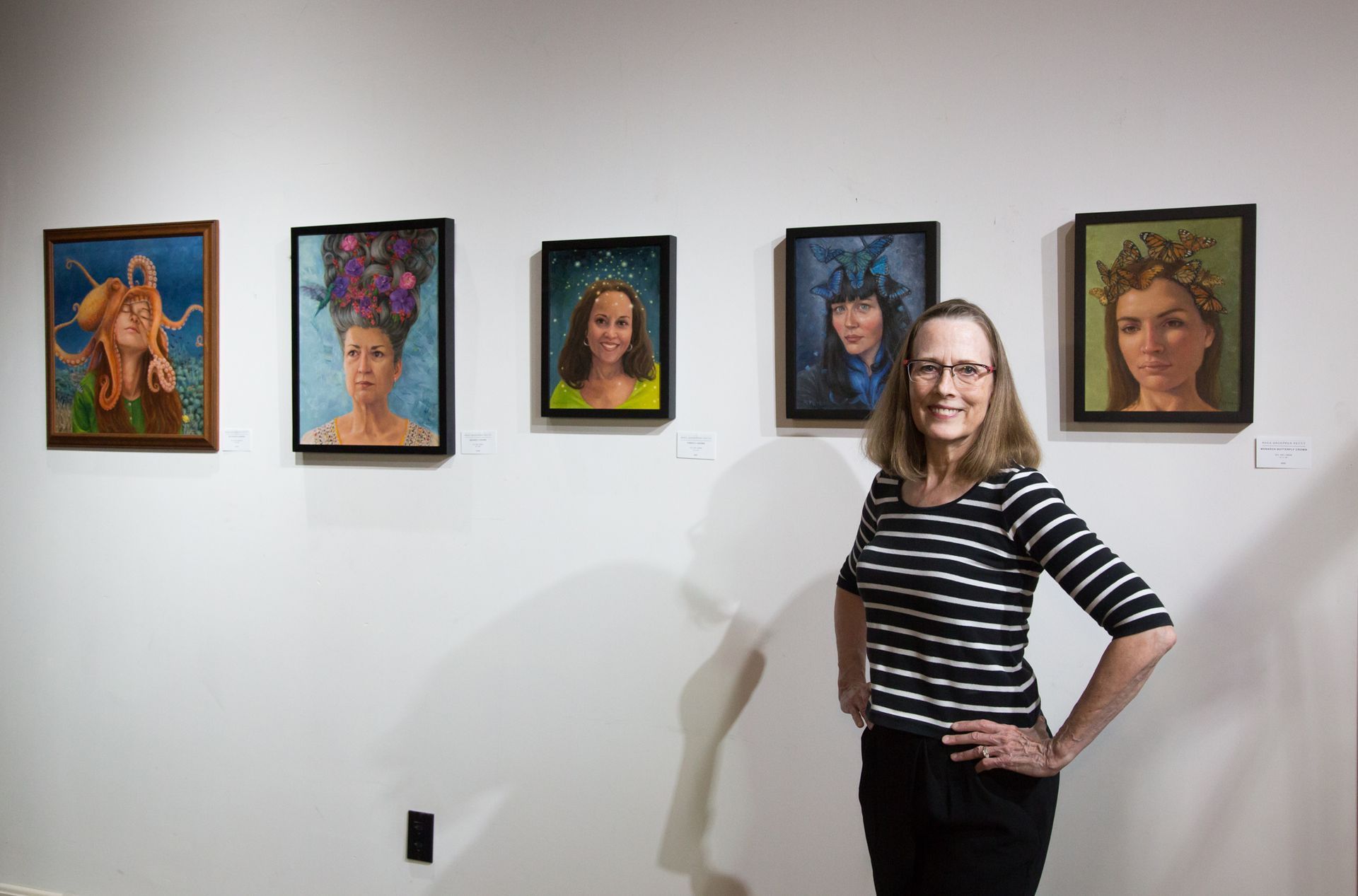 a woman is standing in front of a wall with paintings on it .