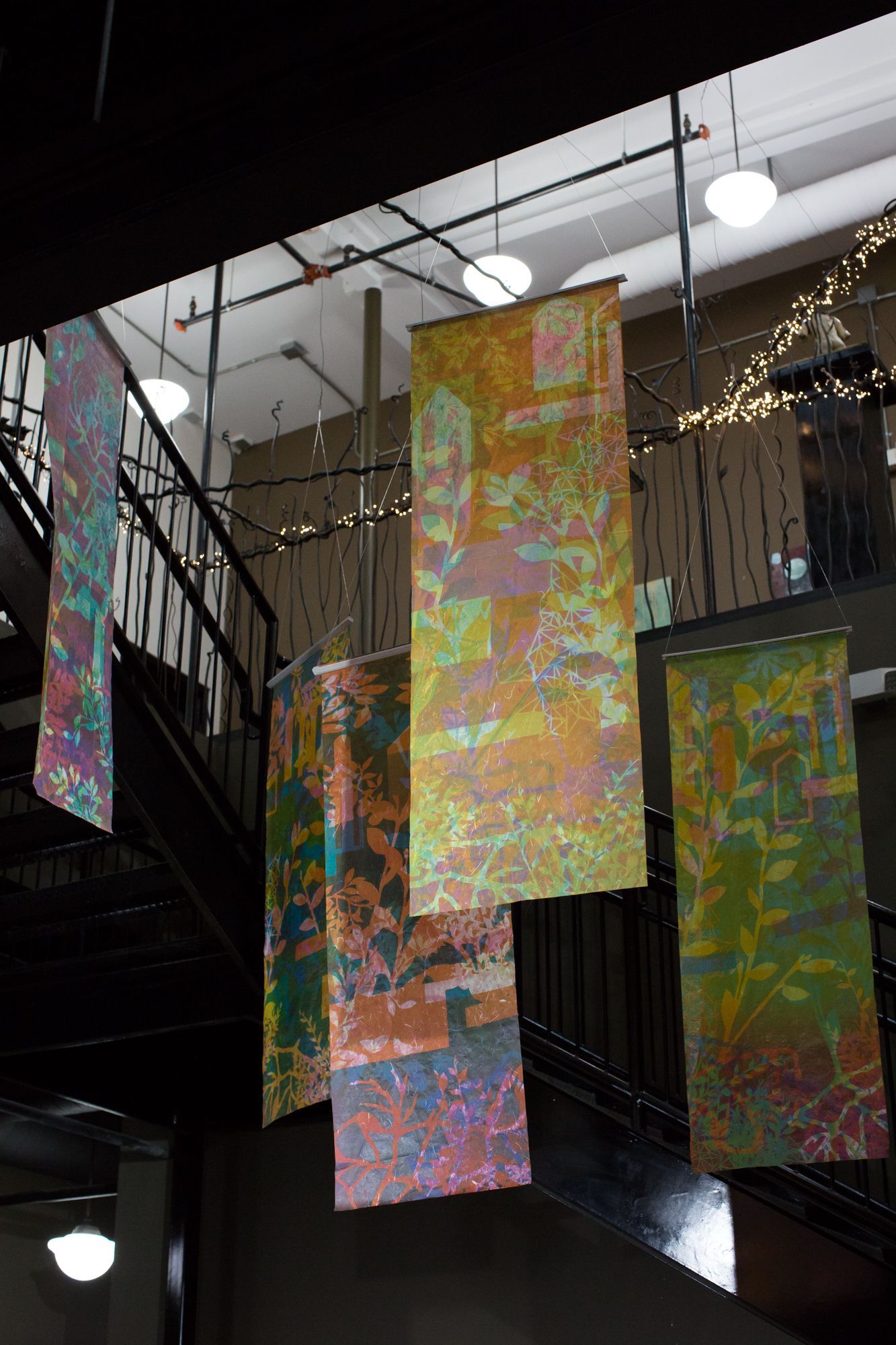 a staircase with a bunch of colorful paintings hanging from the ceiling .