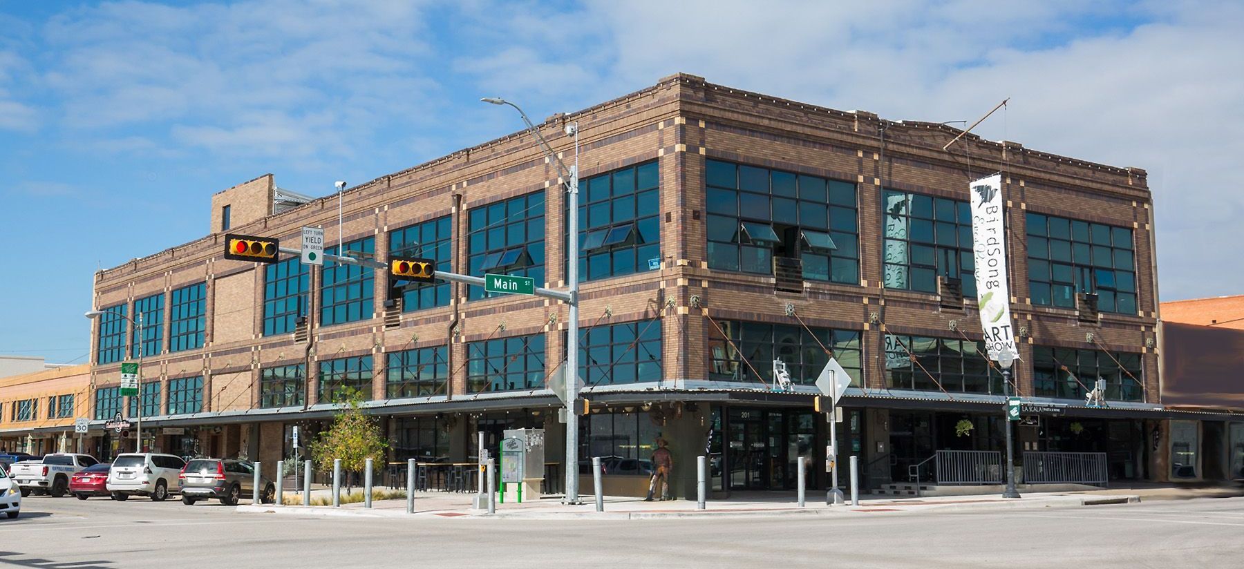 a large brick building with a lot of windows is sitting on the corner of a city street .