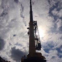 a large crane is silhouetted against a cloudy sky with the sun shining through the clouds .